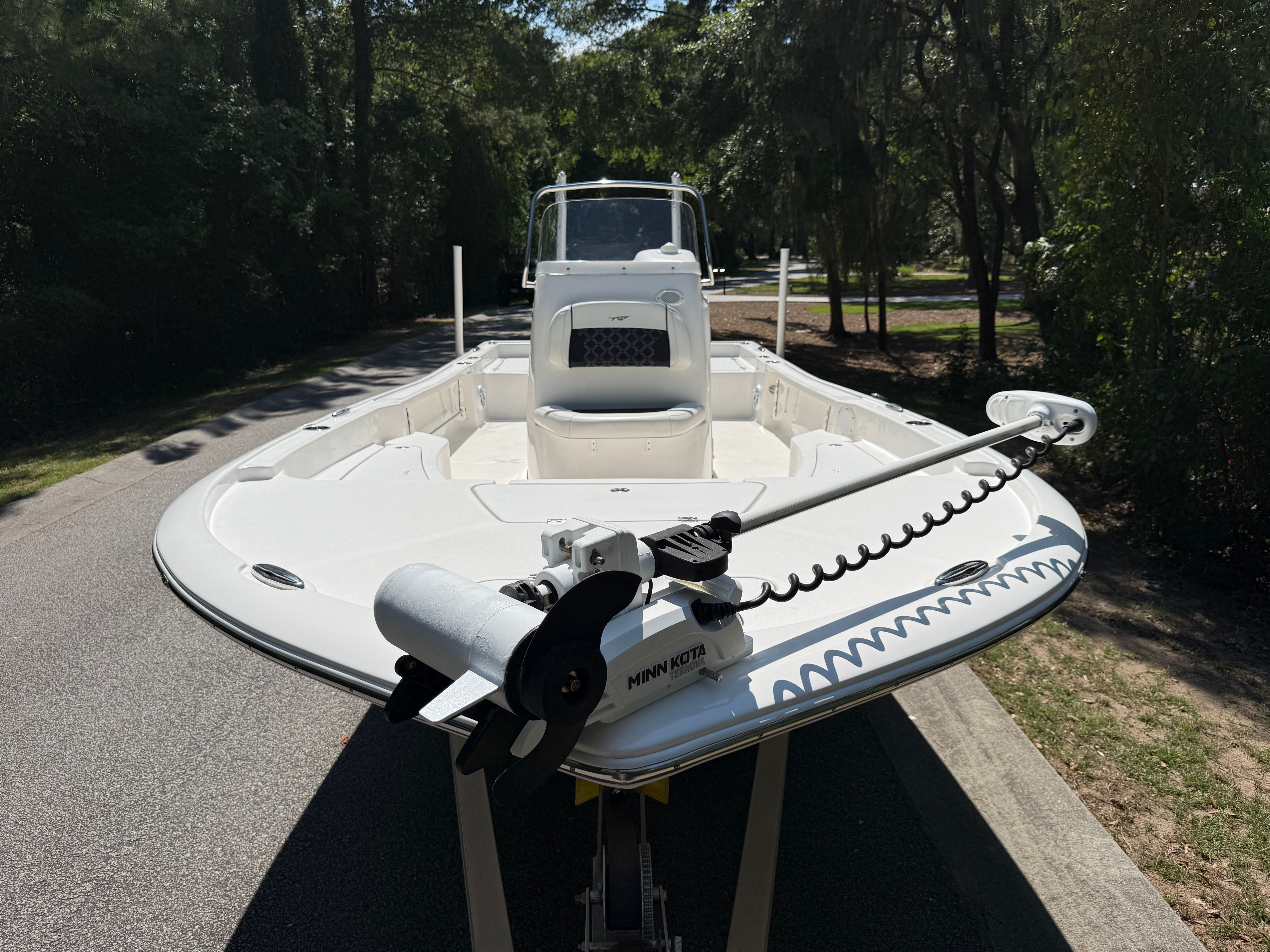 A 2023 Tidewater 2210 Carolina Bay boat on a trailer, surrounded by trees.
