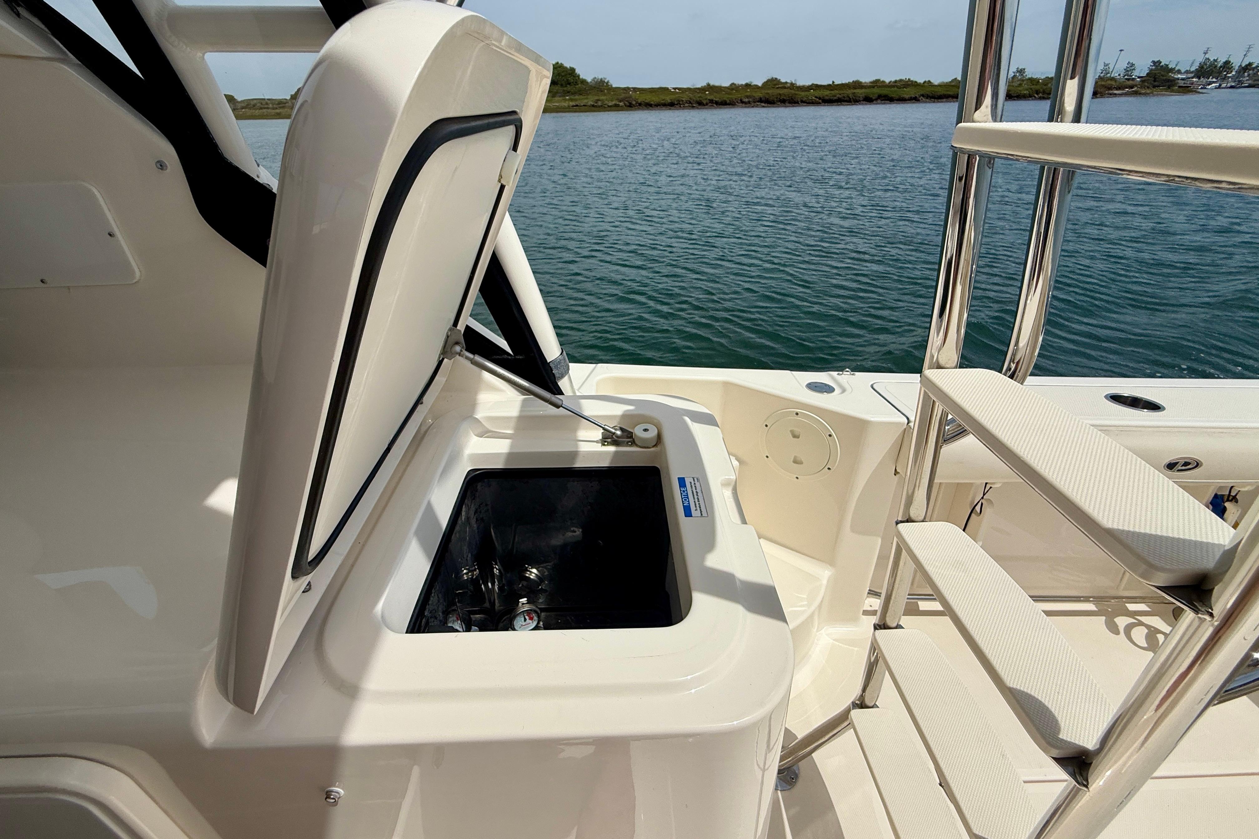 Open storage compartment on 2012 Pursuit OS 345 Offshore boat, near water.