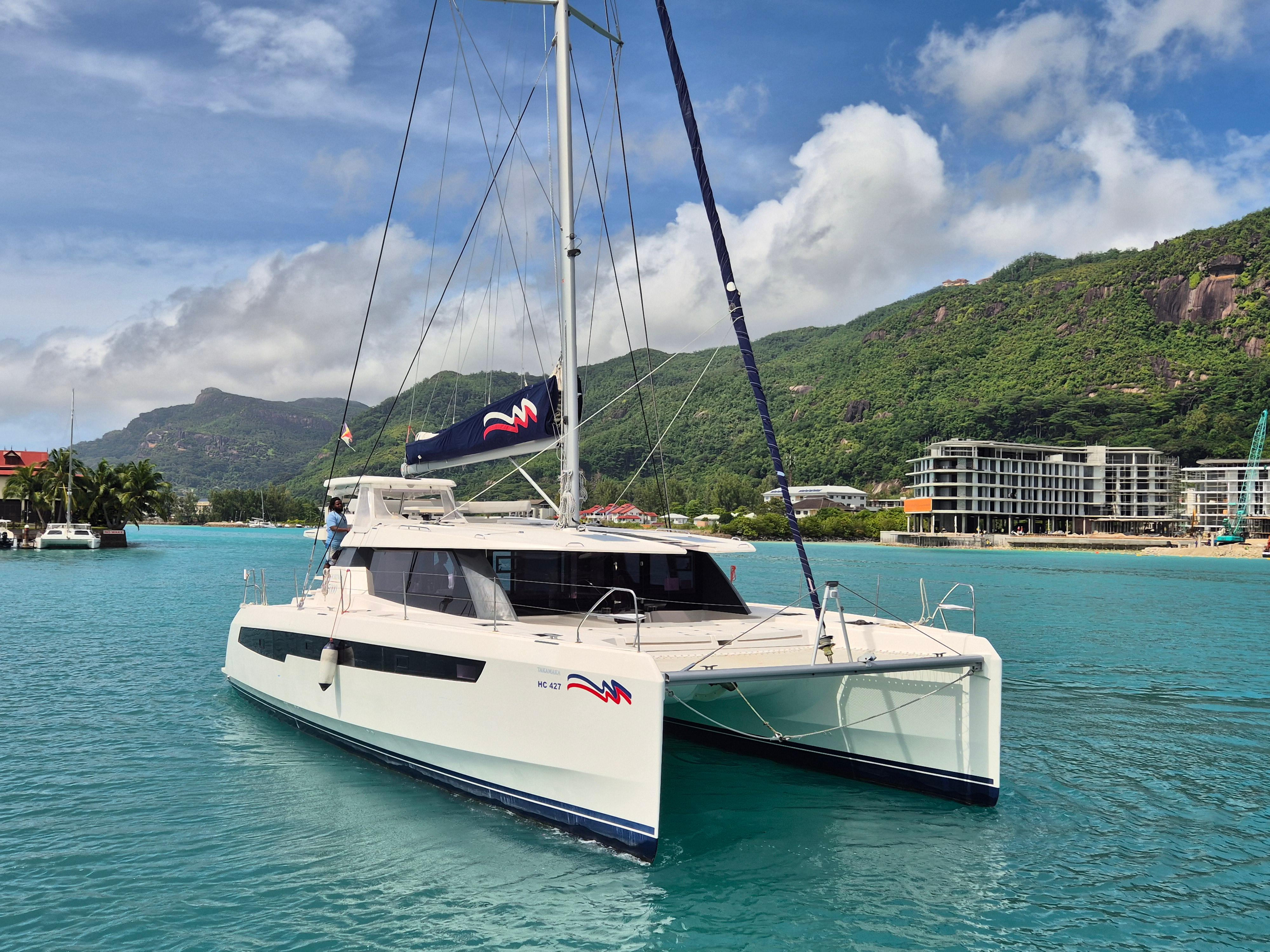 Leopard 50 catamaran sailing in turquoise waters, 2020 model, with scenic mountain backdrop.
