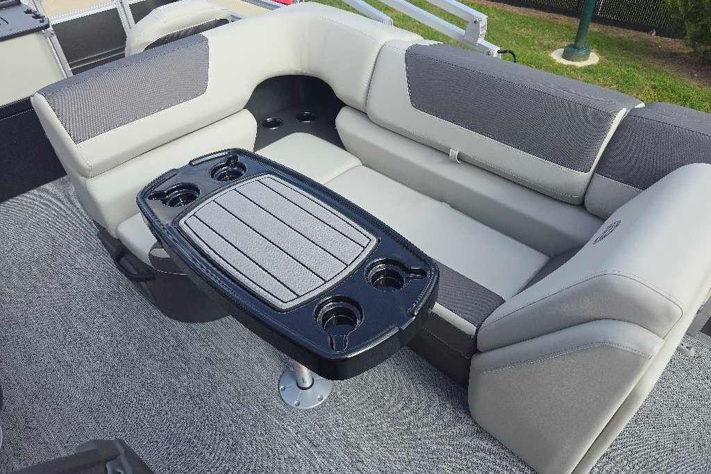 2026 Sun Tracker Fishin' Barge 20 DLX interior with cushioned seating and table with cup holders.