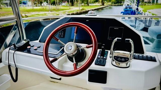 Helm of 2022 Greenline 48 Flybridge with Hardtop, featuring modern controls and red steering wheel.