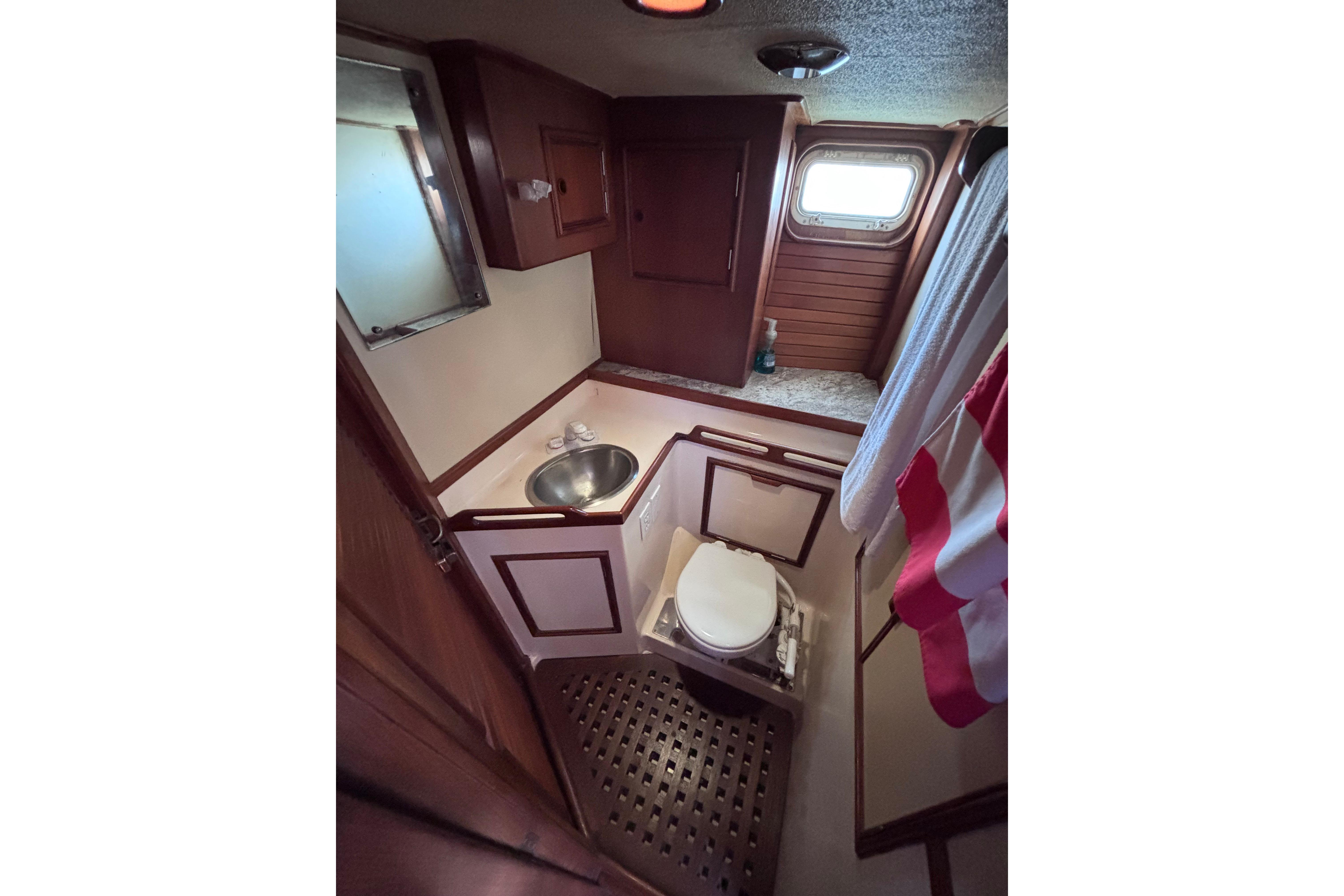 1978 Swift 33 yacht bathroom with wooden cabinetry, sink, and porthole window.