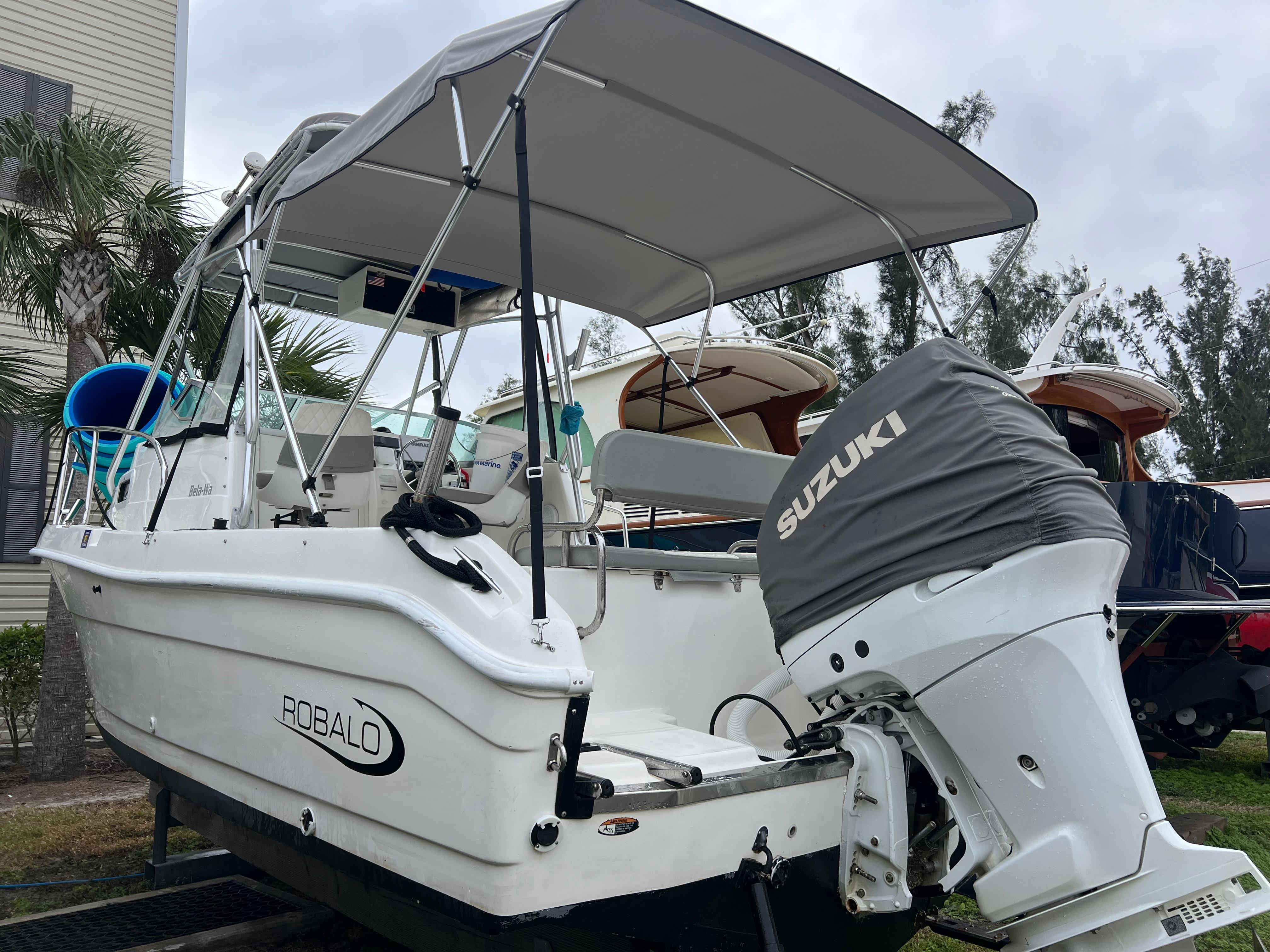 2000 Robalo 2440 Walkaround boat with Suzuki outboard motor, parked outdoors.