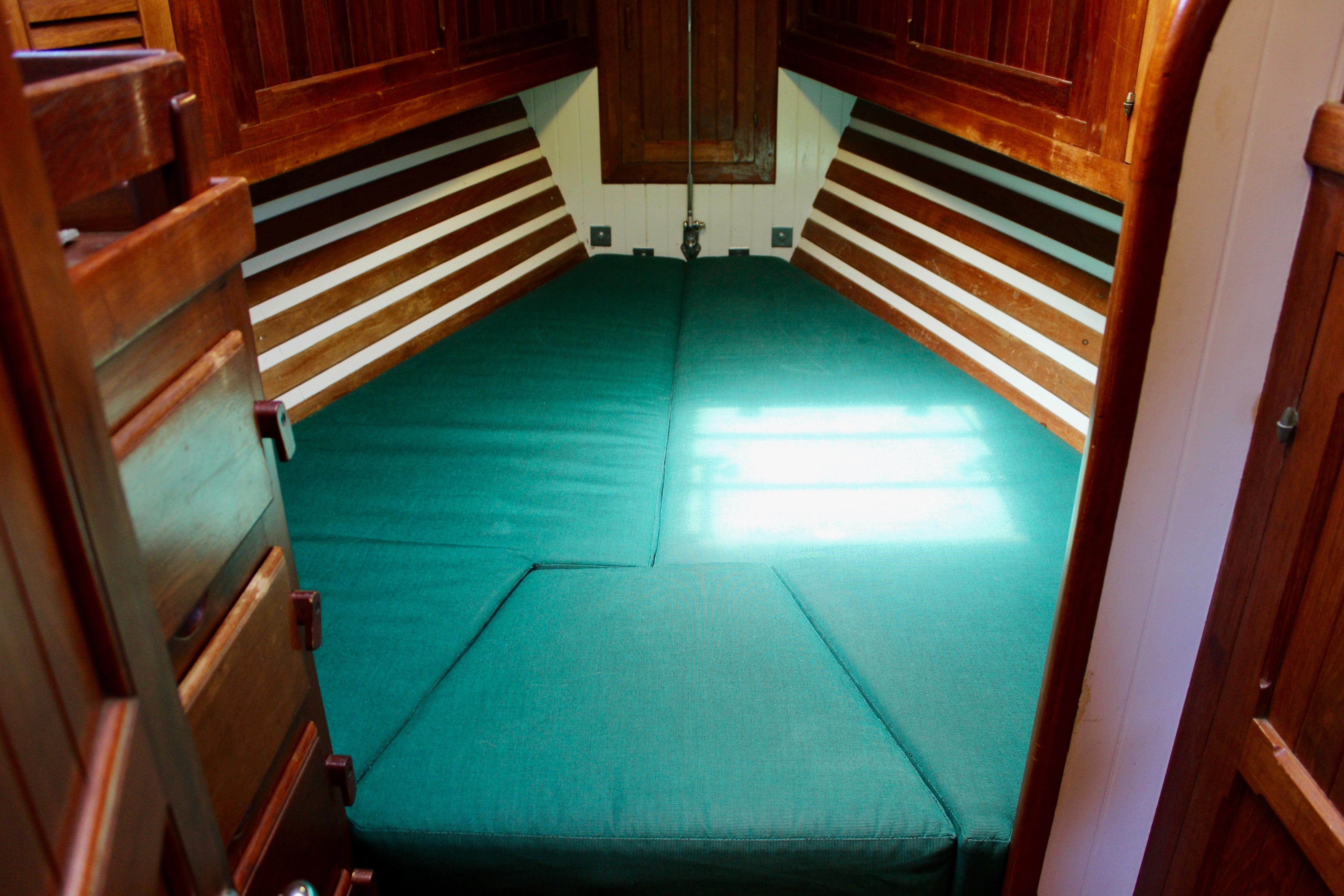 Cozy cabin interior of 1981 Kelly Peterson 46 sailboat with green cushions and wooden accents.