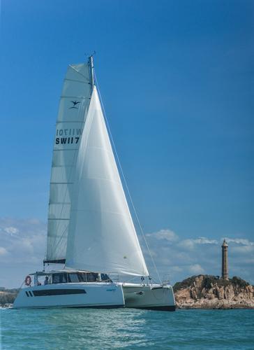 2025 Seawind 1170 catamaran sailing near a coastal lighthouse.