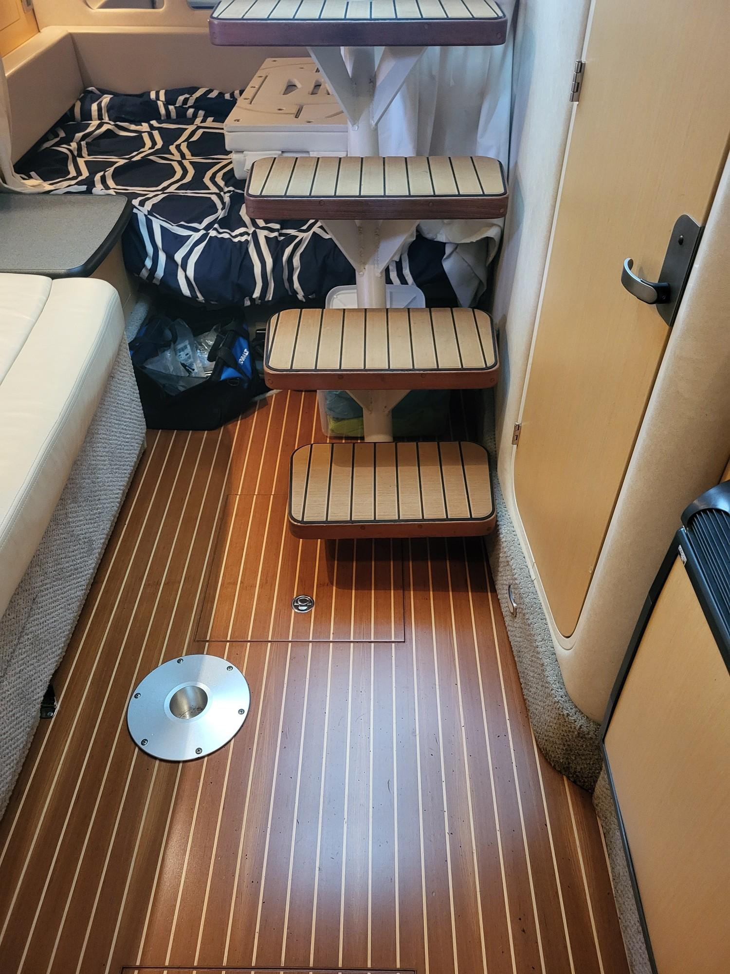 Interior of a 2009 Sea Ray 310 Sundancer with wooden flooring and compact stairs.