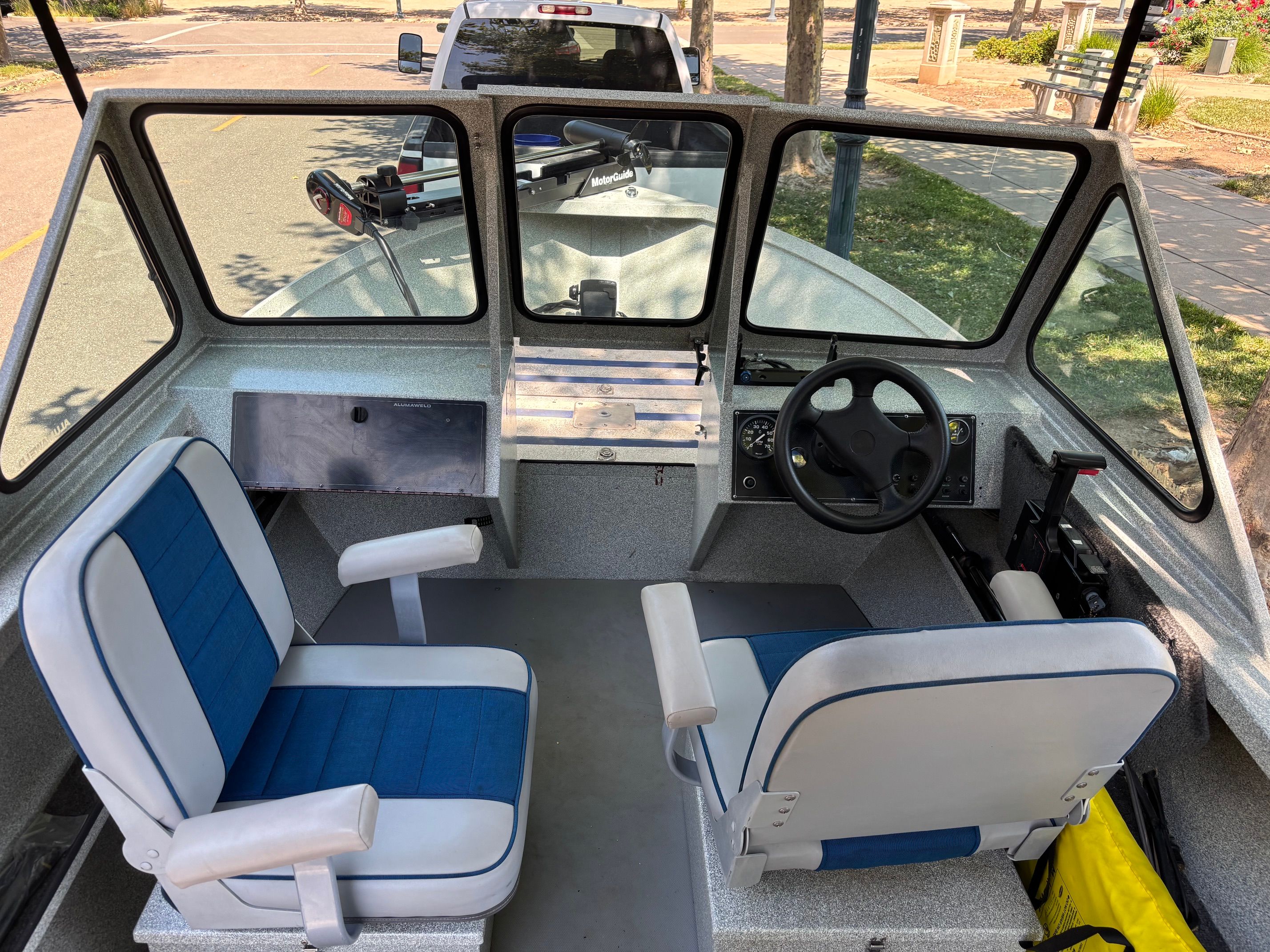 Interior view of a 2002 Stryker Rogue boat with two blue seats and a steering wheel.