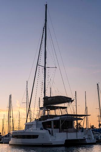 Sailing catamaran Bali 4.8, 2021 model, docked at sunset with masts silhouetted.