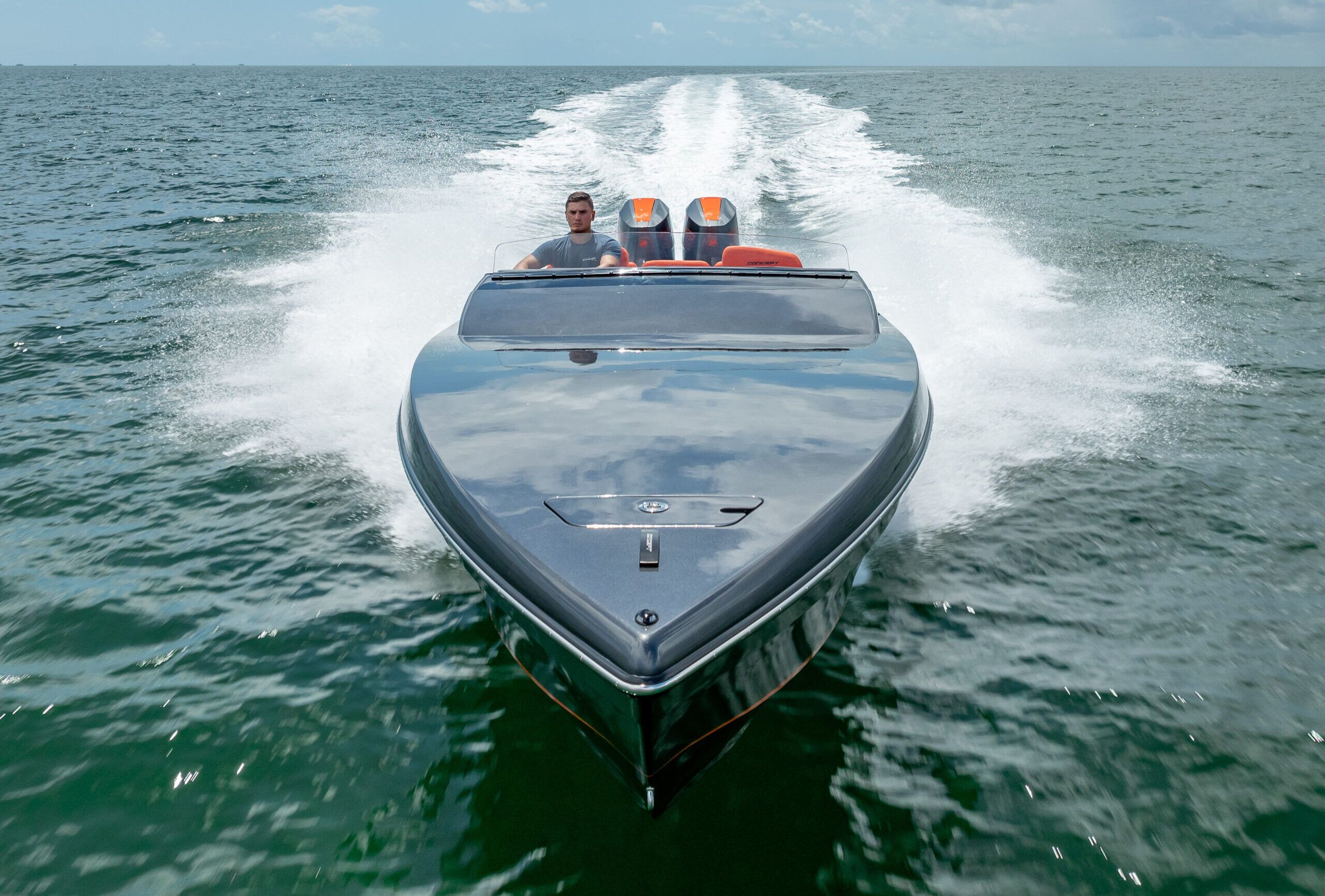 A sleek motorboat speeds across open water, with a driver at the helm.