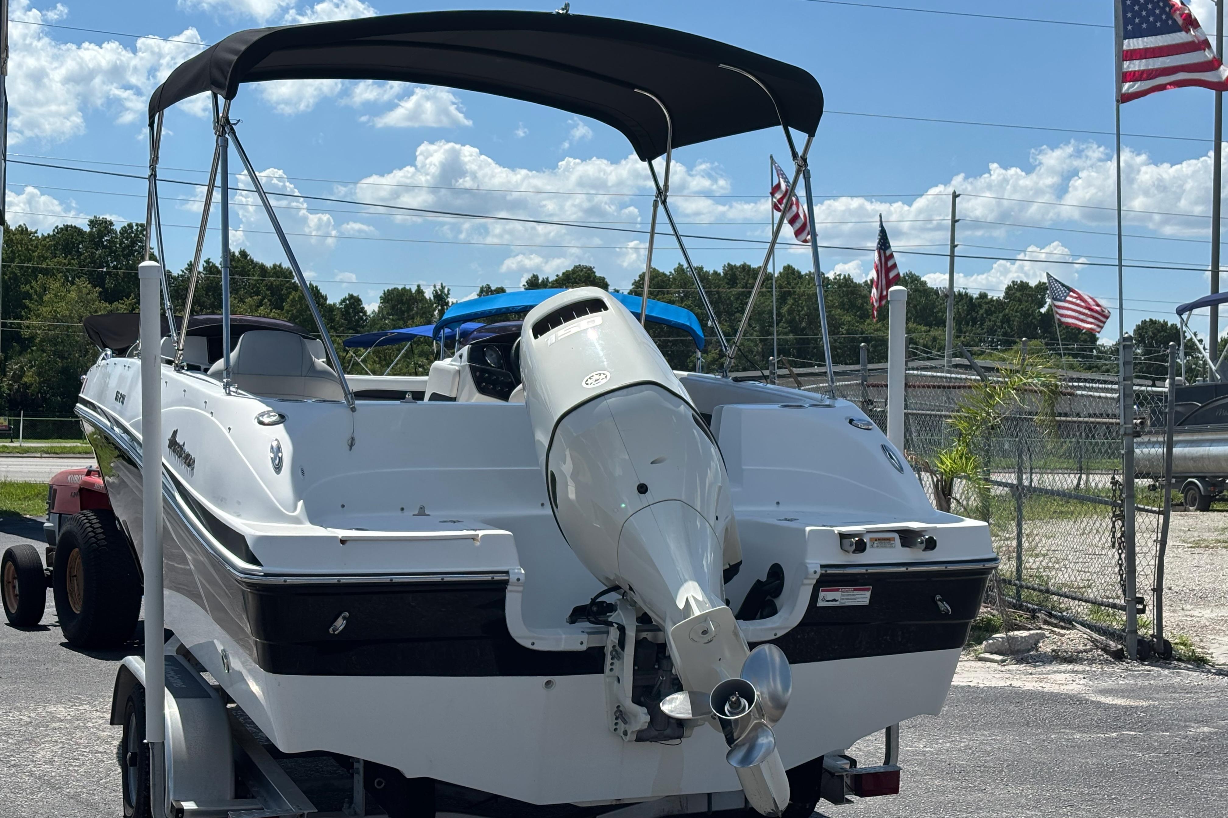 2019 Hurricane Sundeck Sport 218 OB boat on trailer, with American flags in background.