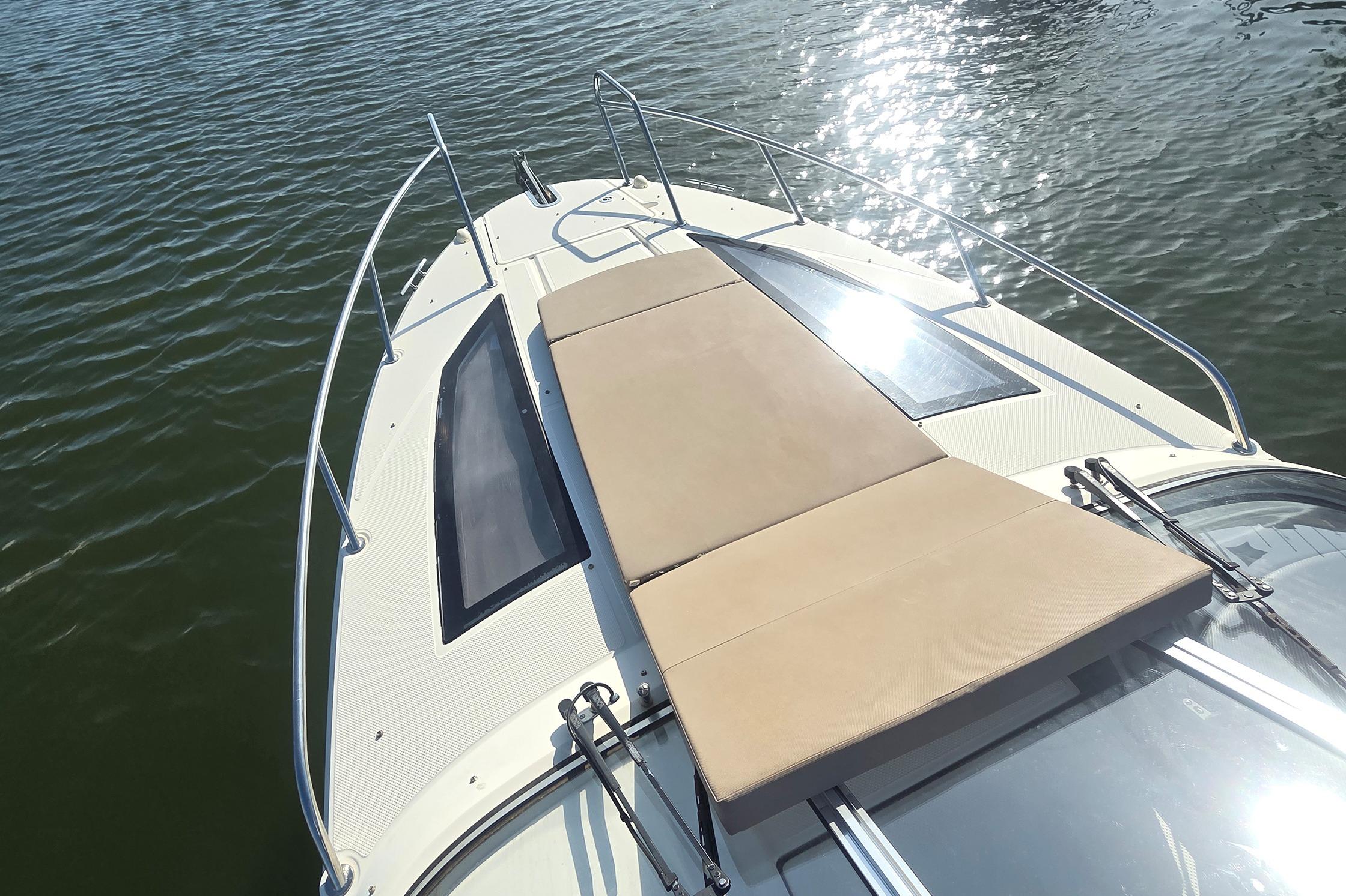 2017 Quicksilver Activ 805 Cruiser deck with sunbed, reflecting sunlight on water.