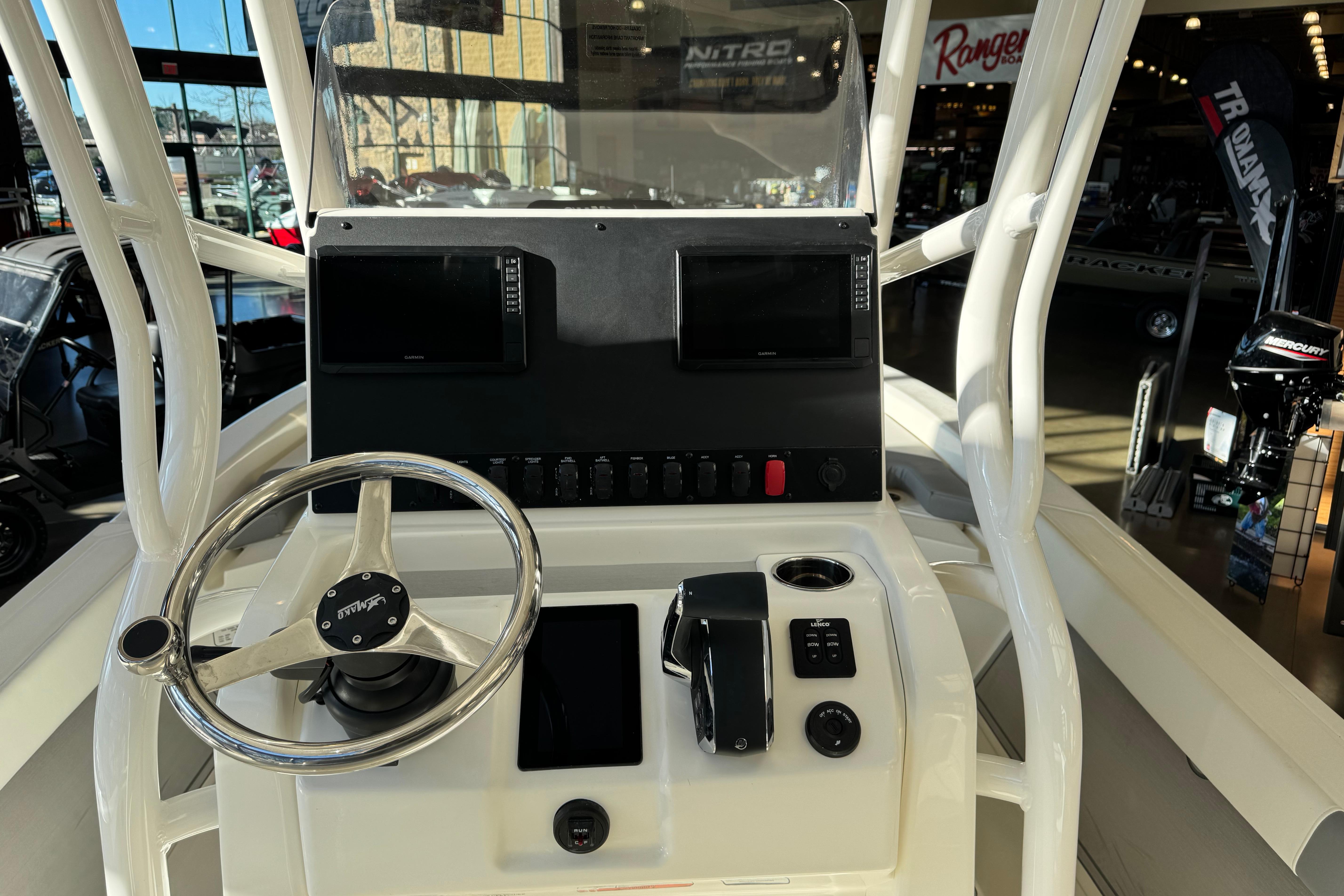 2026 Mako 24 APEX boat console with steering wheel and dual displays in showroom.