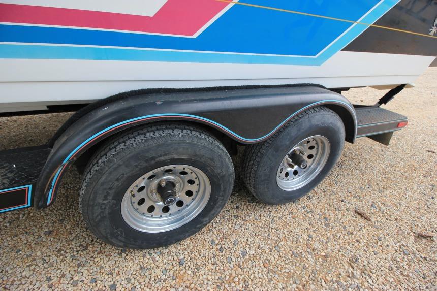 1989 Formula 223 SS boat trailer with dual wheels on gravel surface.
