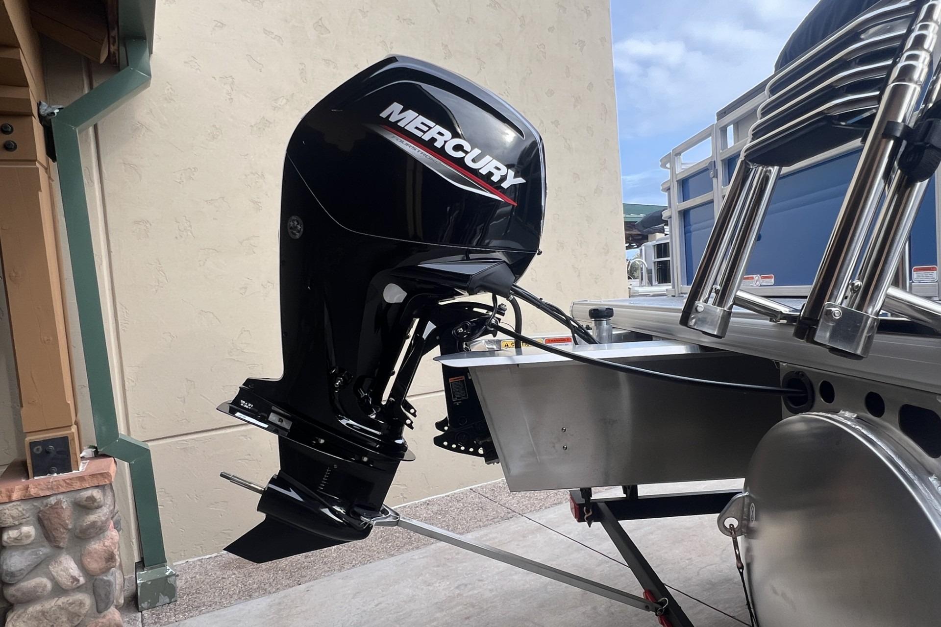 2026 Sun Tracker Fishin' Barge 20 DLX with Mercury outboard motor, docked outdoors.