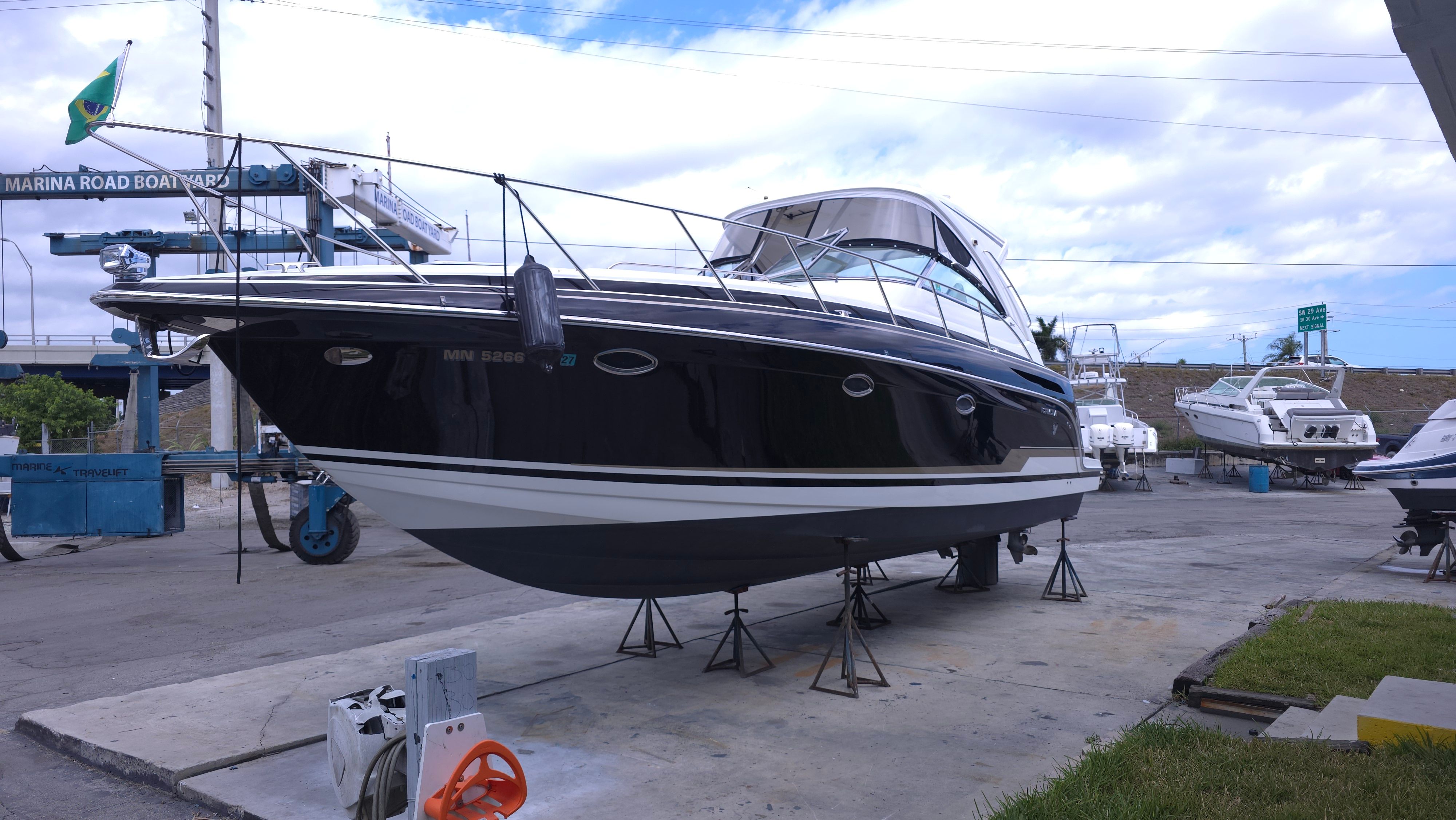 A black motorboat is on a dry dock. It has a white canopy and is surrounded by other boats.