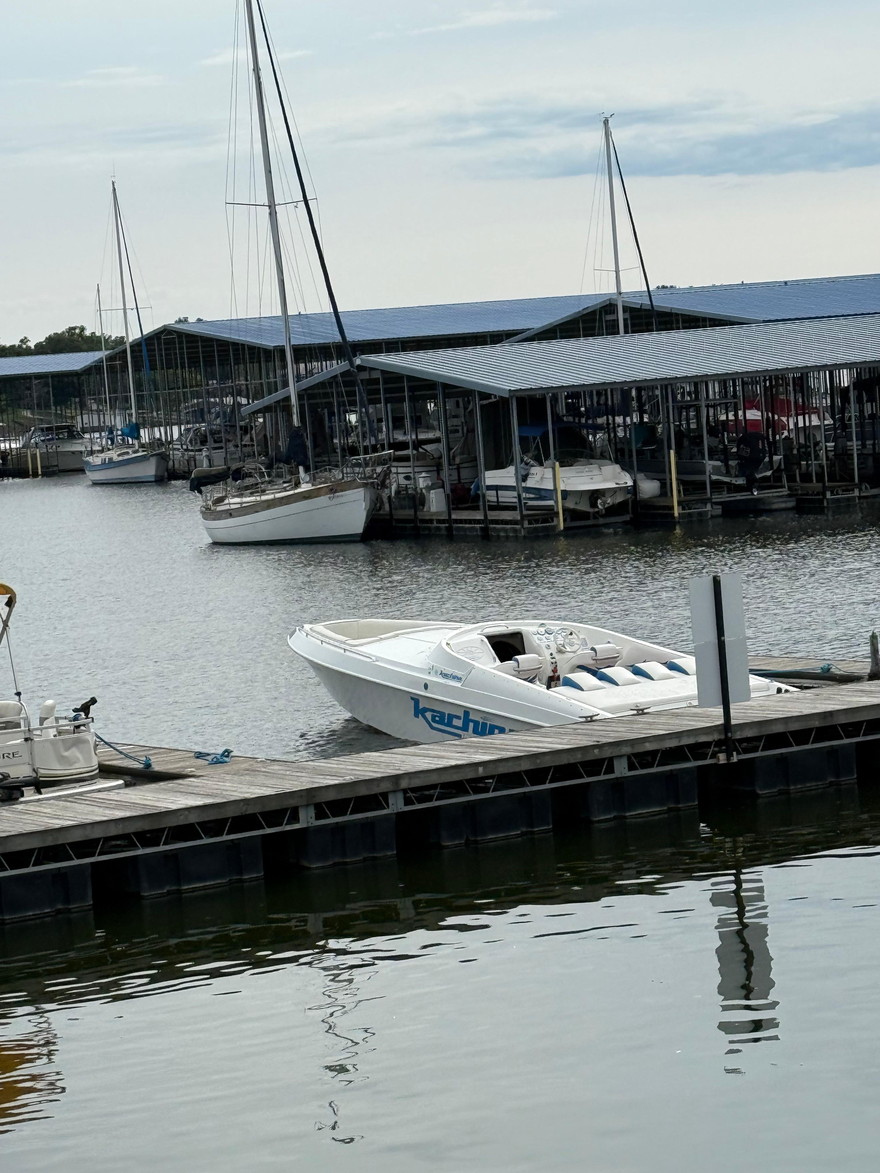 2005 Kachina Bolero boat docked at a marina with covered sailboats.