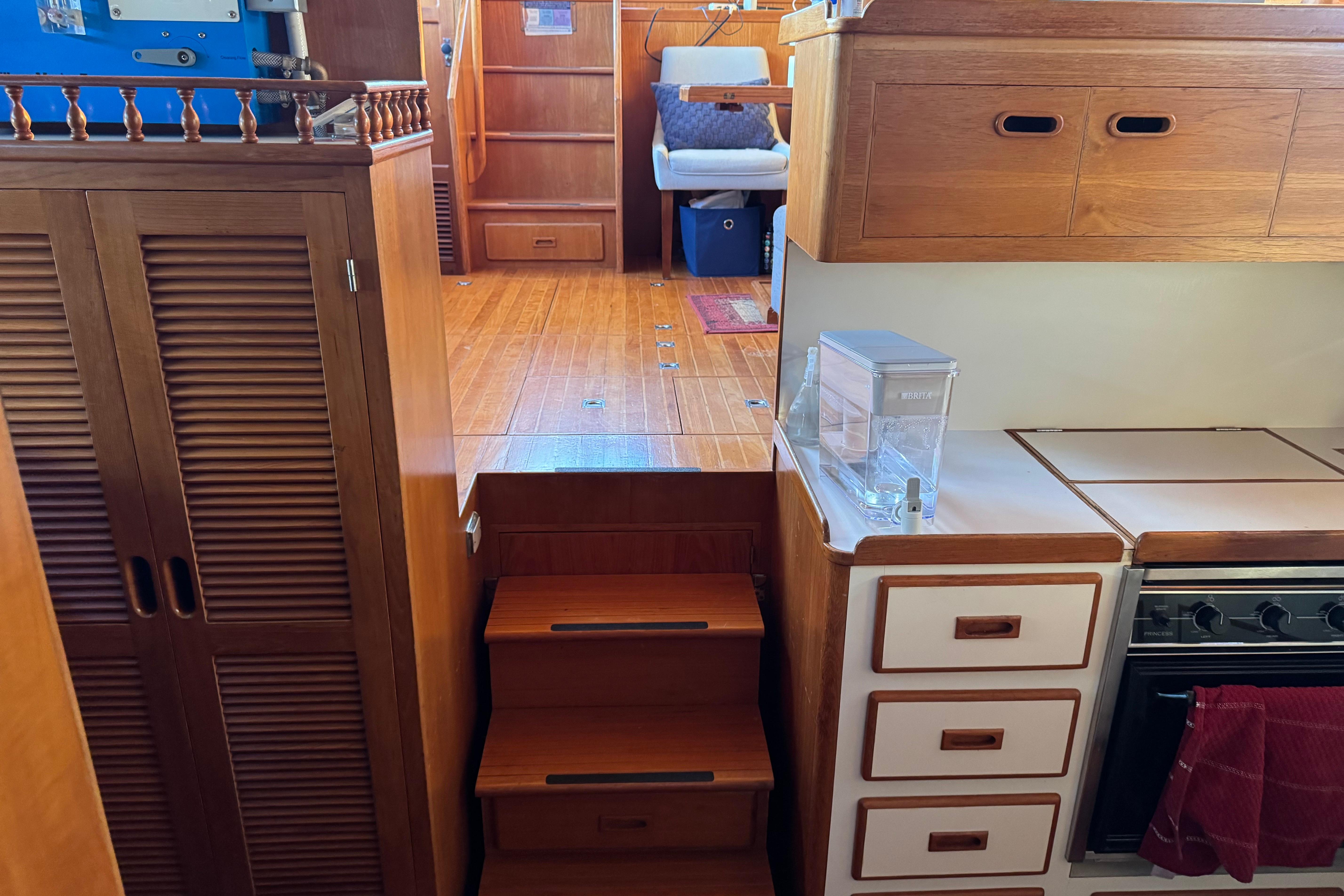 Interior of a 1987 President 37 yacht with wooden cabinetry and compact kitchen.