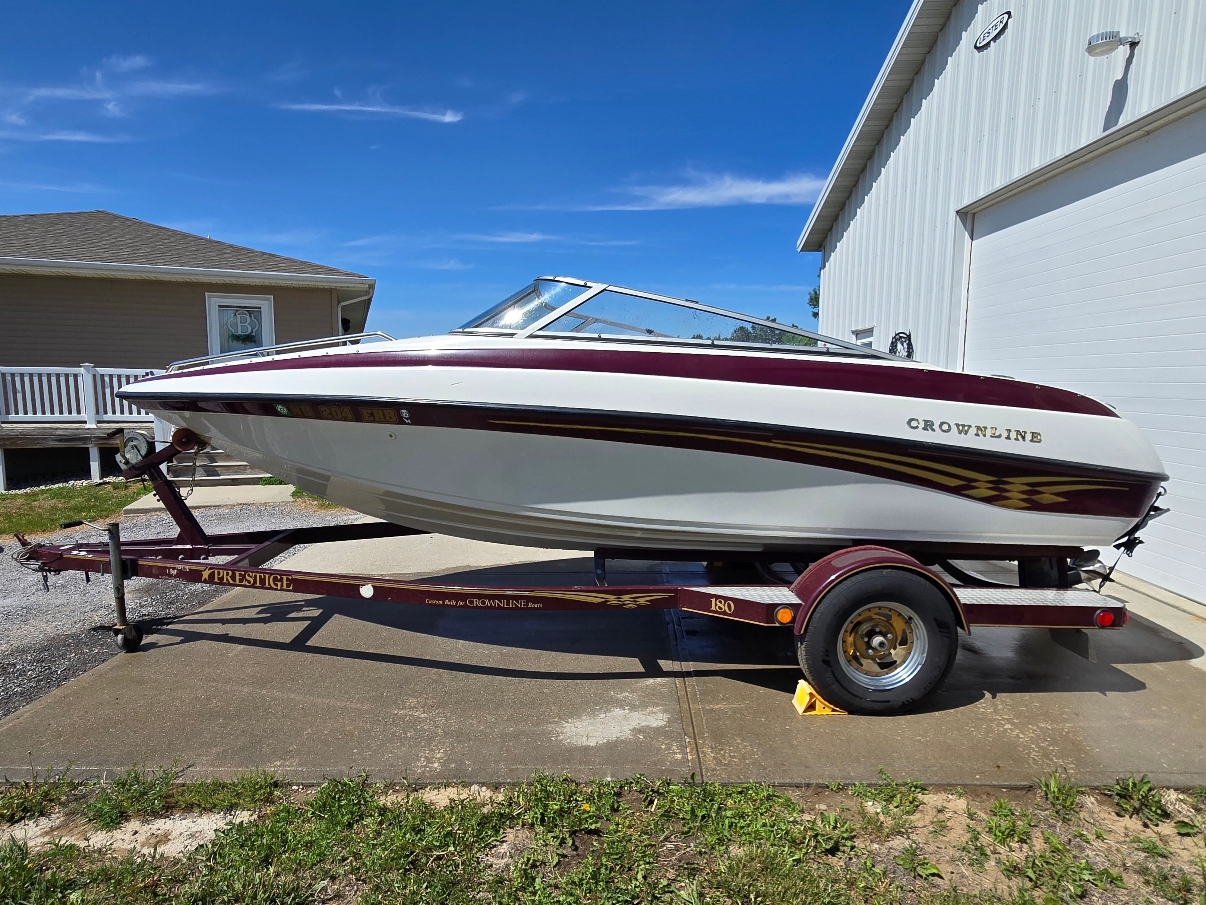 A 2001 Crownline 180 BR boat on a trailer beside a building.
