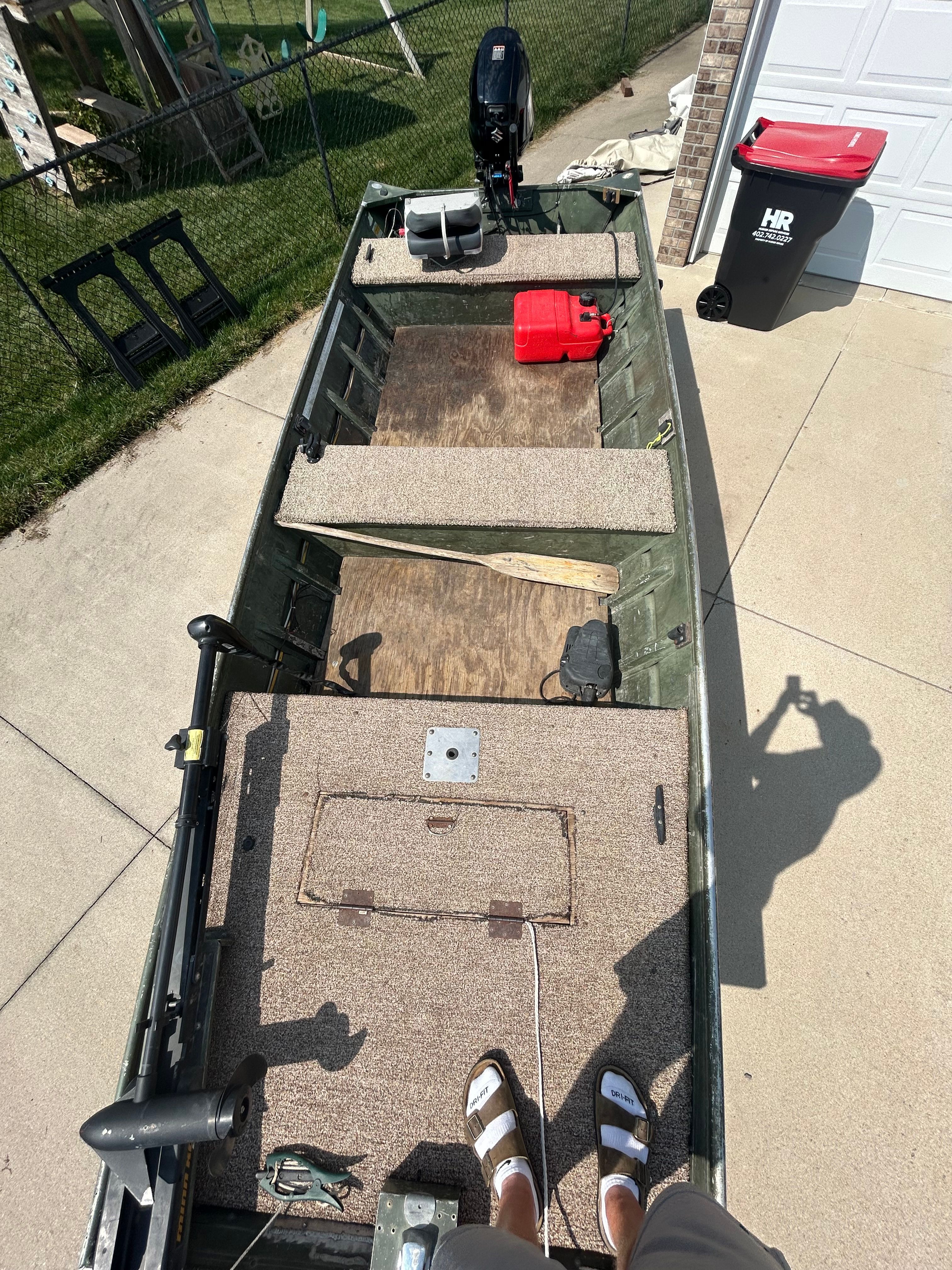 1992 Alumacraft 1648 Jon boat with carpeted interior and motor, parked on driveway.