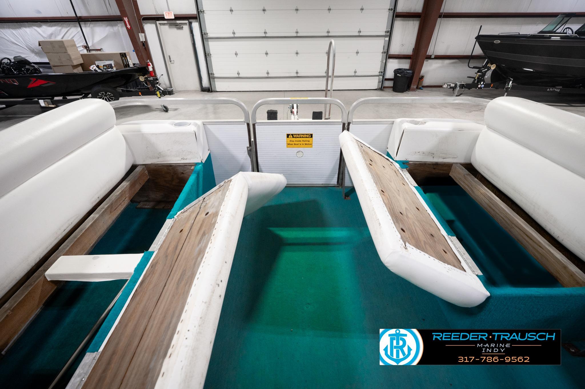 1992 Godfrey Sweetwater boat interior with white seating and teal flooring in a garage.