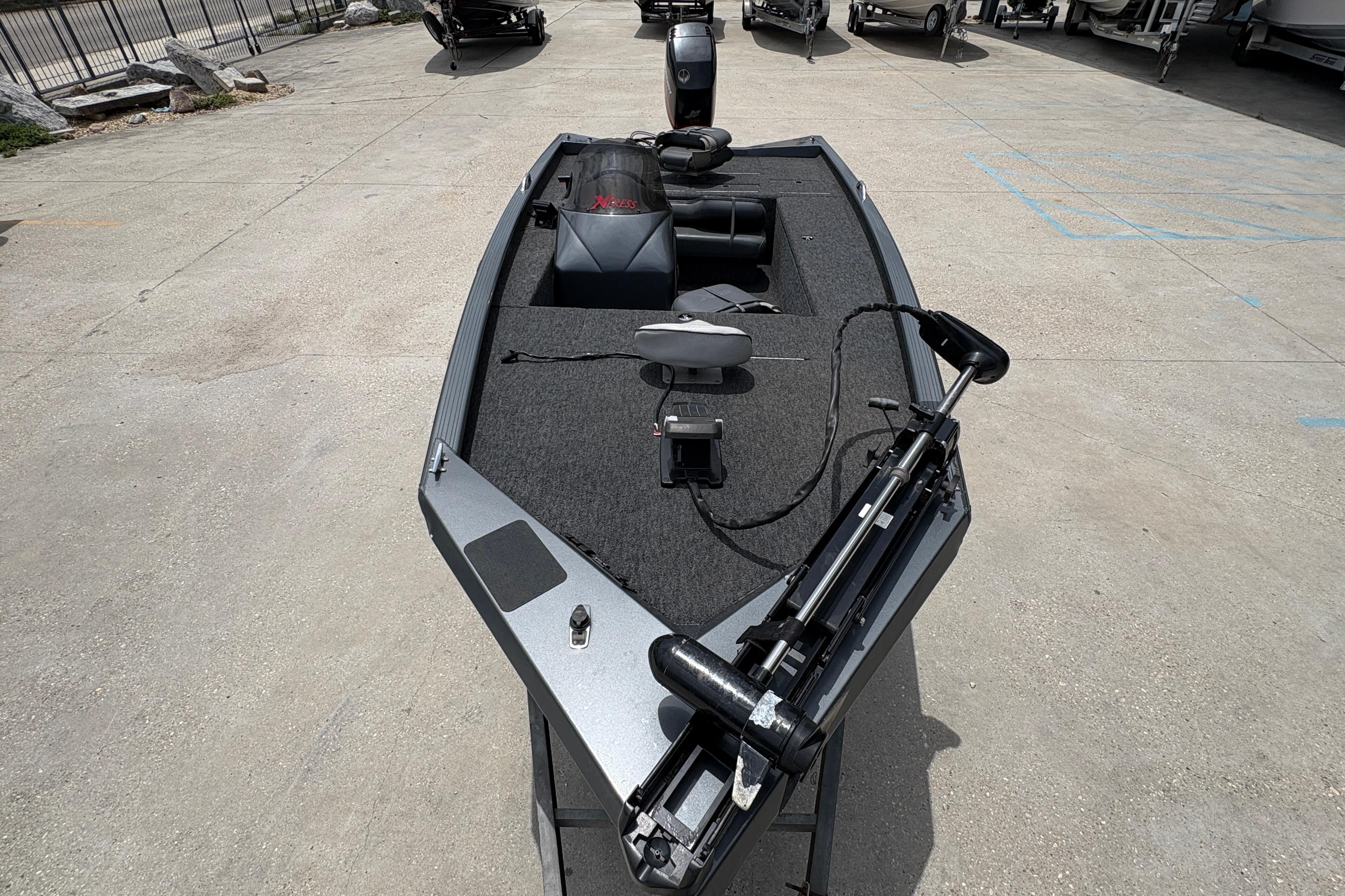 2000 Xpress X18 boat with trolling motor on concrete lot.