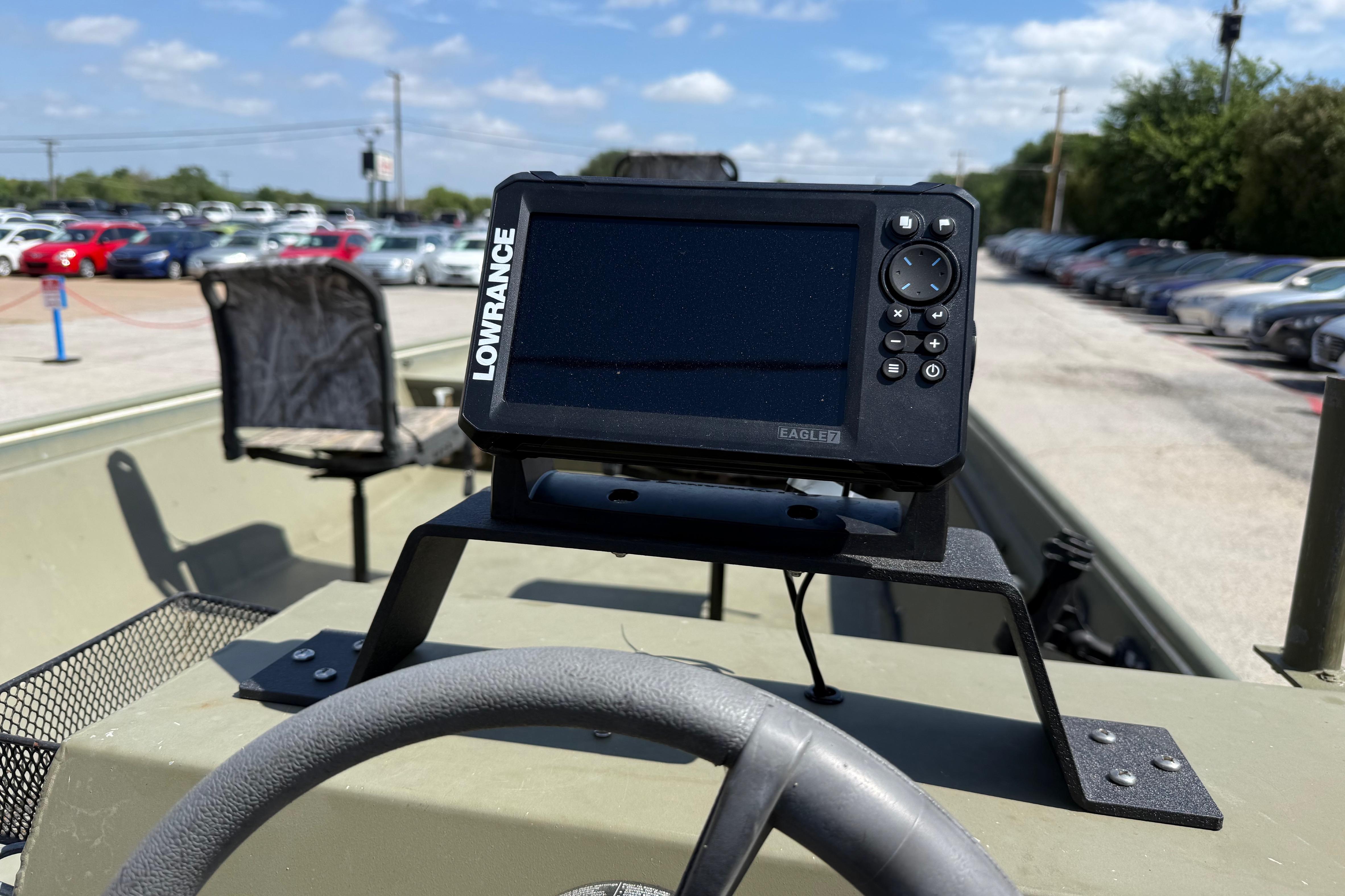A Lowrance fish finder is mounted on a boat, surrounded by cars in a parking lot.
