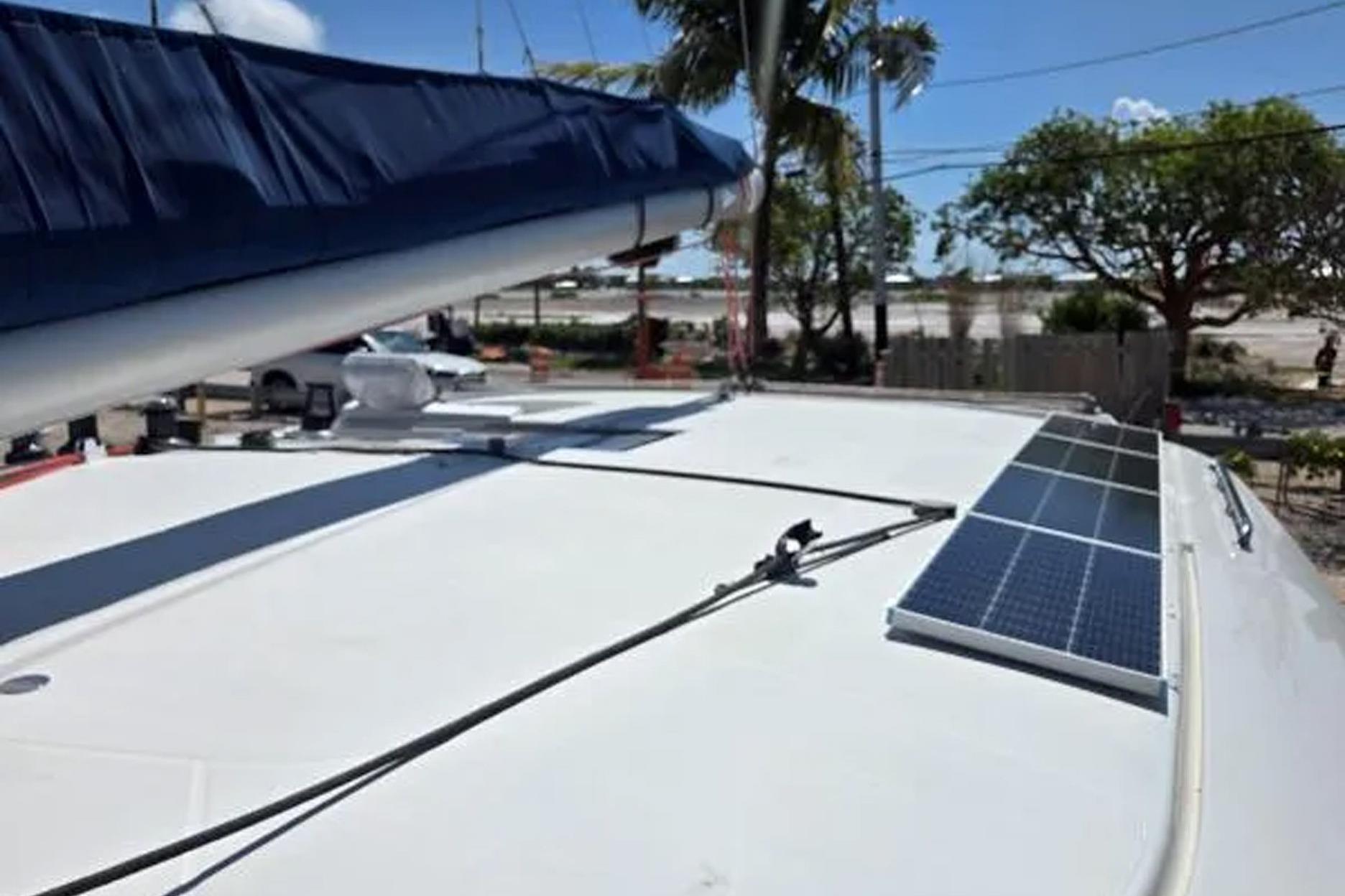 2008 Fountaine Pajot Salina 48 catamaran with solar panels on deck, docked near palm trees.