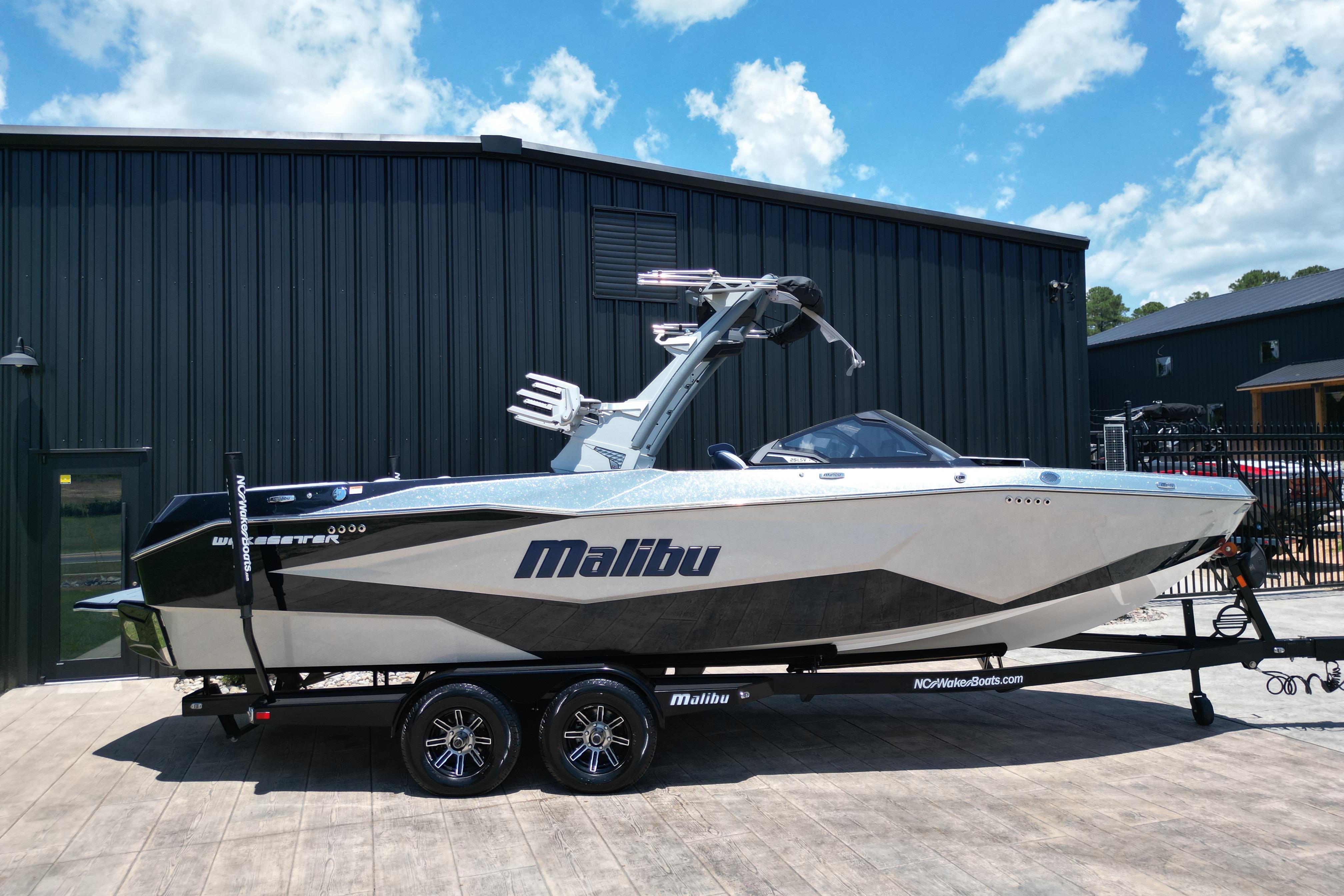 2025 Malibu Wakesetter 25 LSV boat on trailer, parked outside a black building.