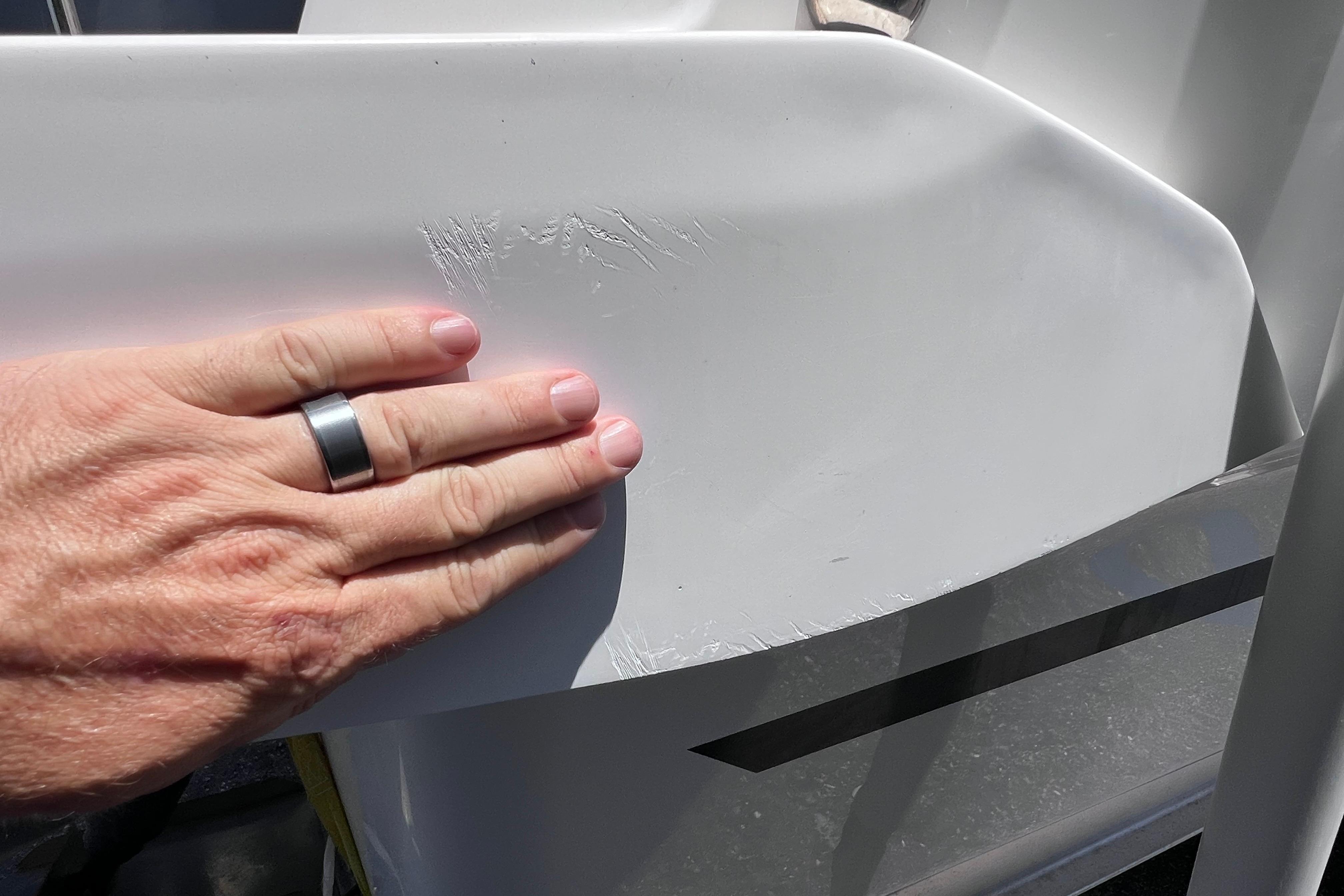 Hand inspecting scratches on 2021 Jeanneau NC Weekender 795 Series 2 boat hull.
