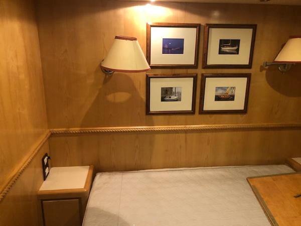 Interior cabin of a 1997 Bertram Convertible yacht with framed pictures and wall lamps.
