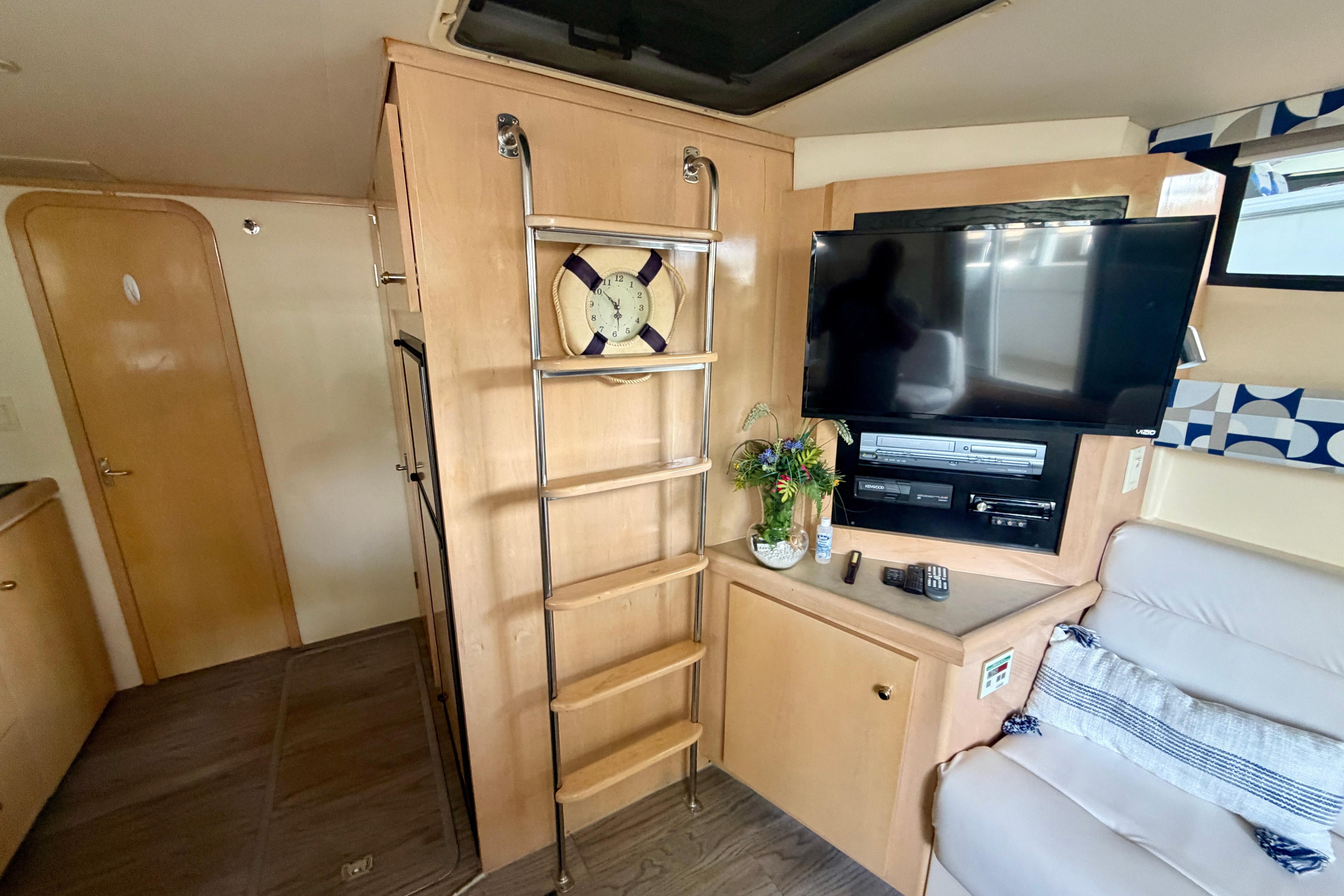Interior of 2000 Carver 350 Mariner yacht with TV, ladder, and cozy seating area.