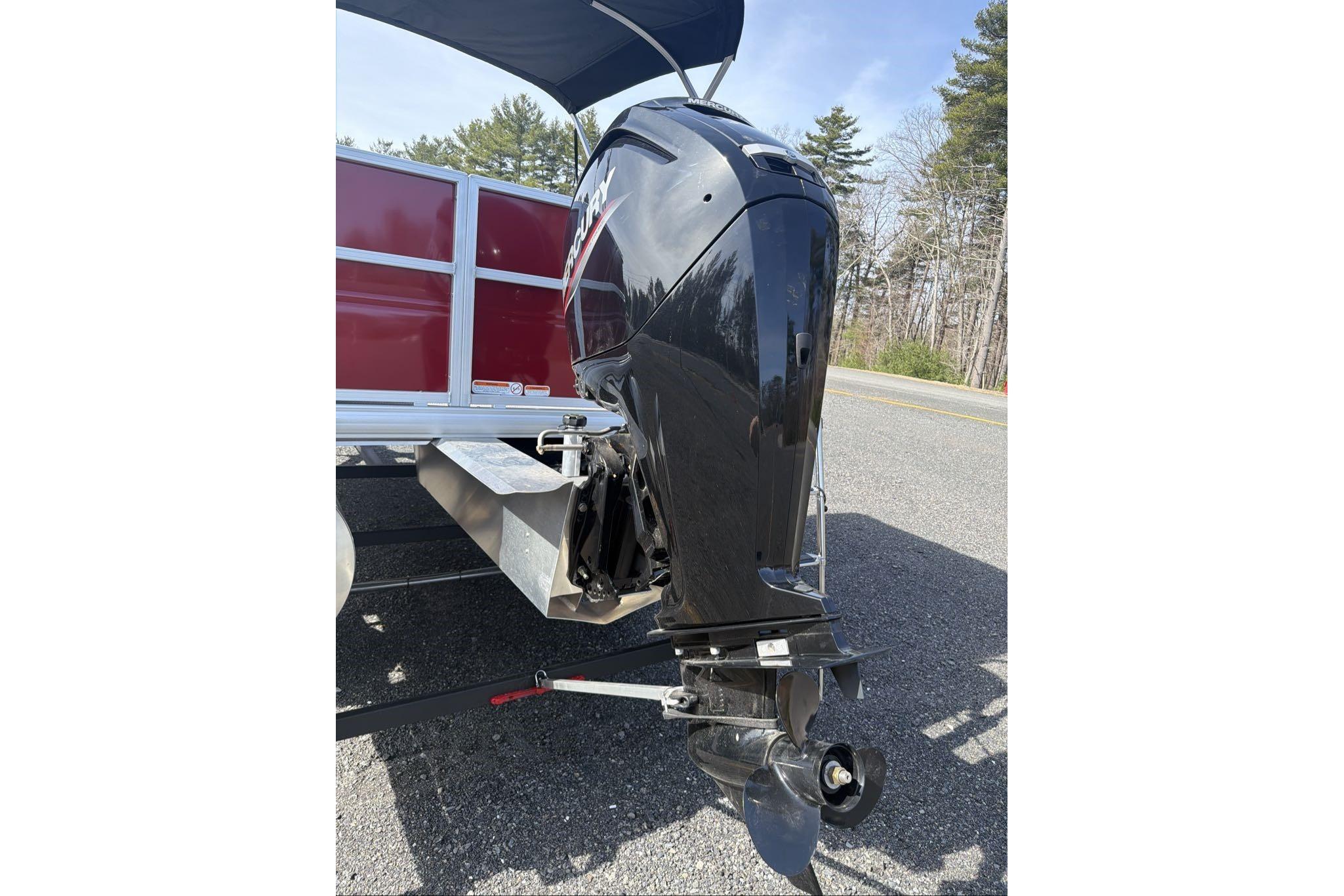 2026 Sun Tracker Party Barge 18 DLX with Mercury outboard motor on a road.