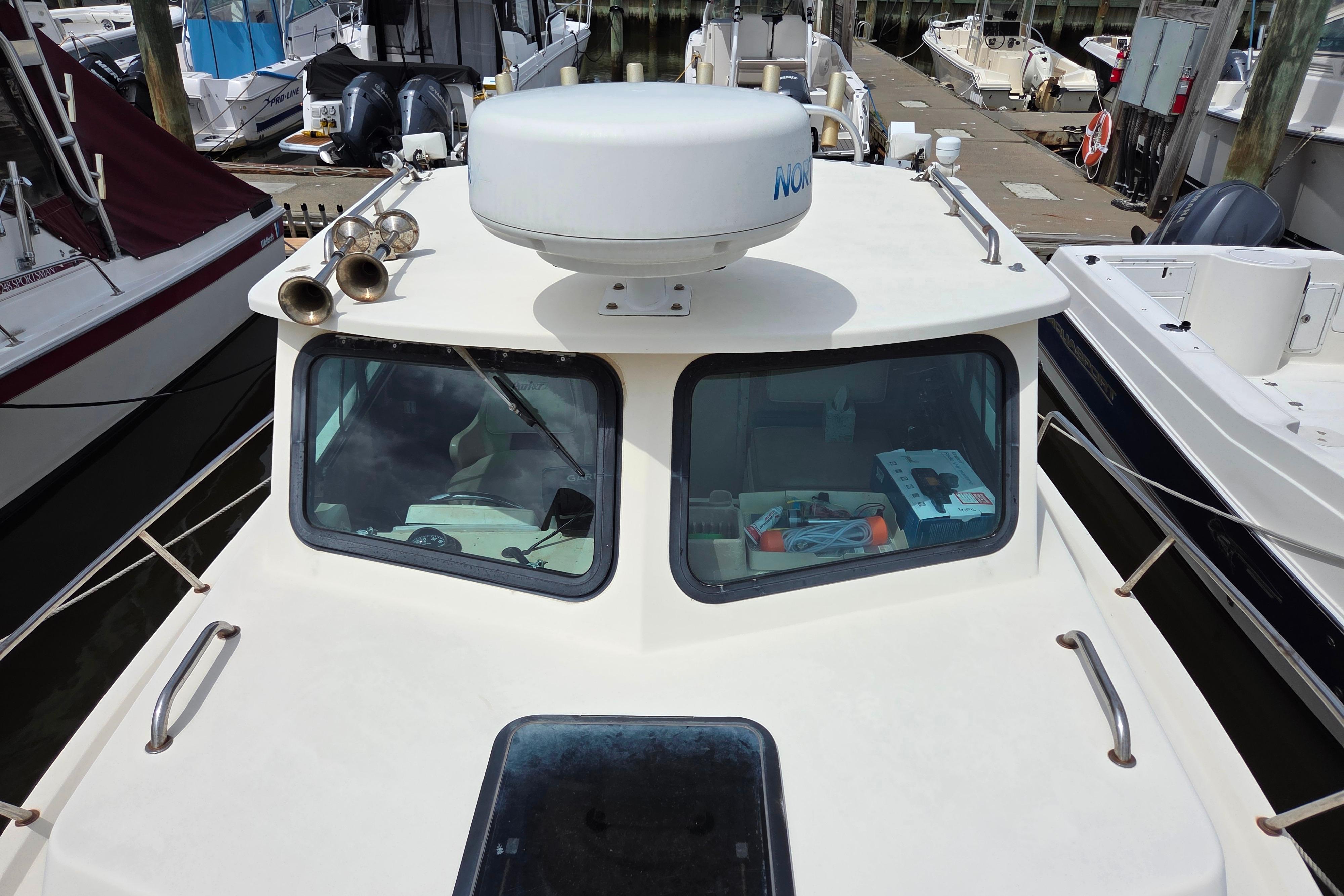 2002 Parker 2520 Deep Vee Sport Cabin boat docked at marina, featuring radar and cabin view.