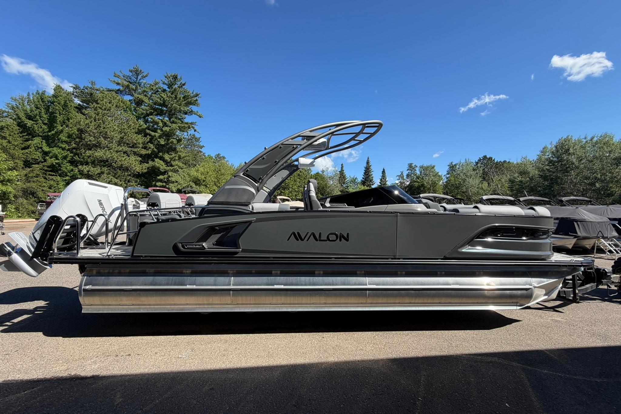 2026 Avalon Excalibur LTD Quad Lounge pontoon boat with sleek design and windshield, parked outdoors.