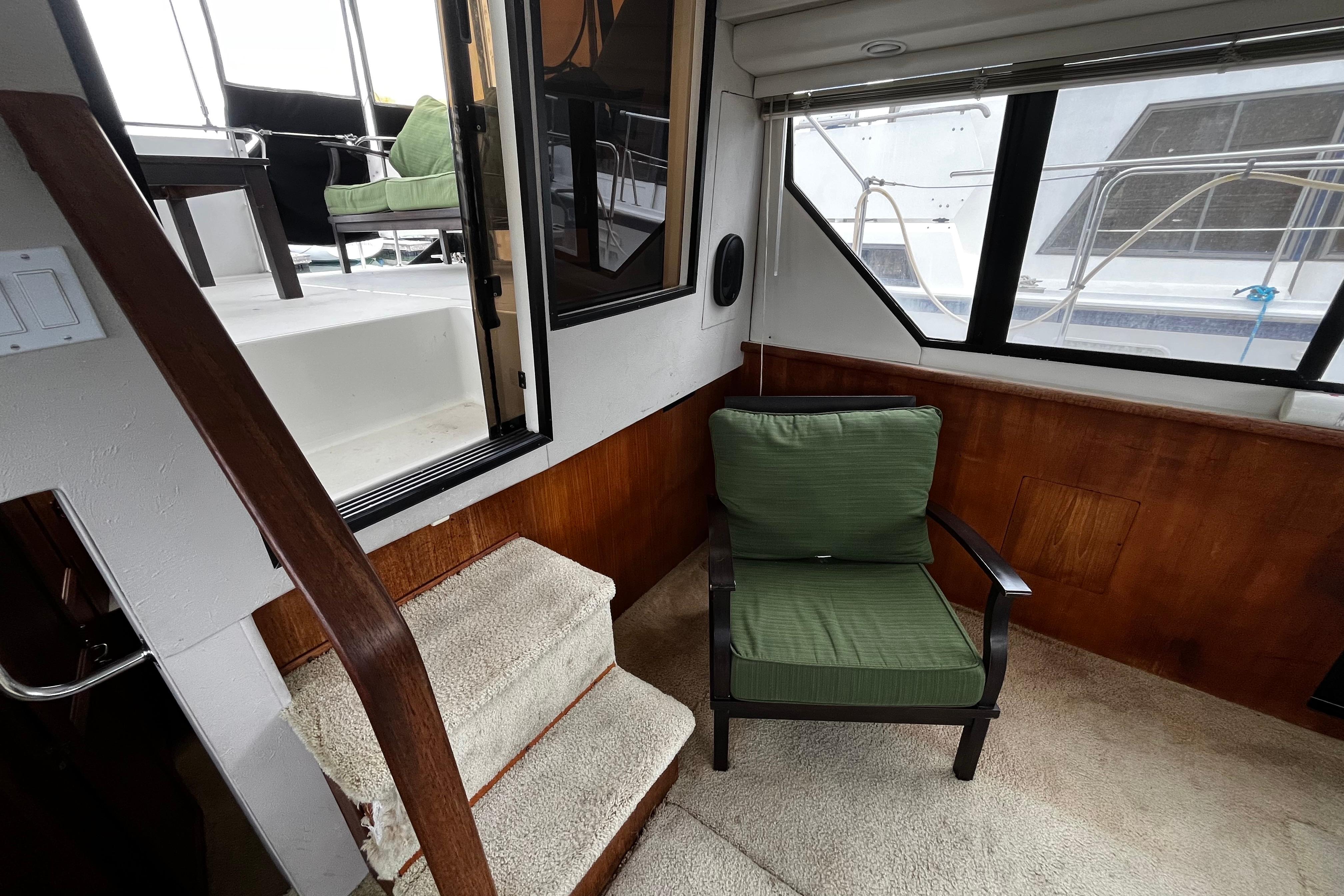 1991 Carver 33 Aft Cabin Motor Yacht interior with green chair and carpeted stairs.