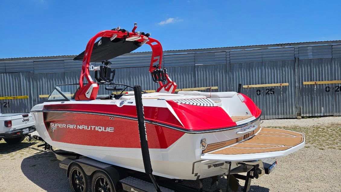 A red and white boat on a trailer, featuring a prominent tower.