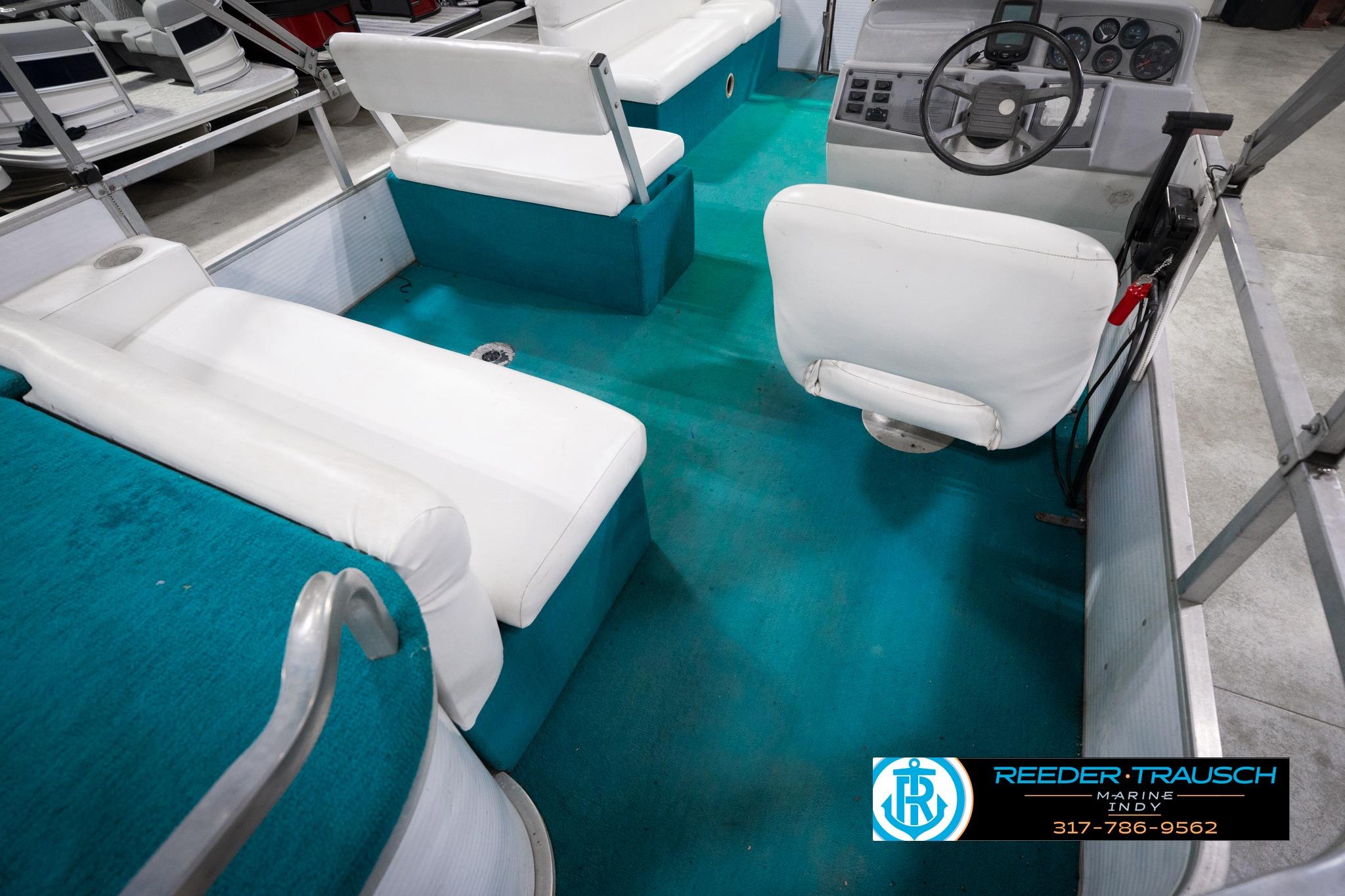 Interior of a 1992 Godfrey Sweetwater boat with teal flooring and white seating.