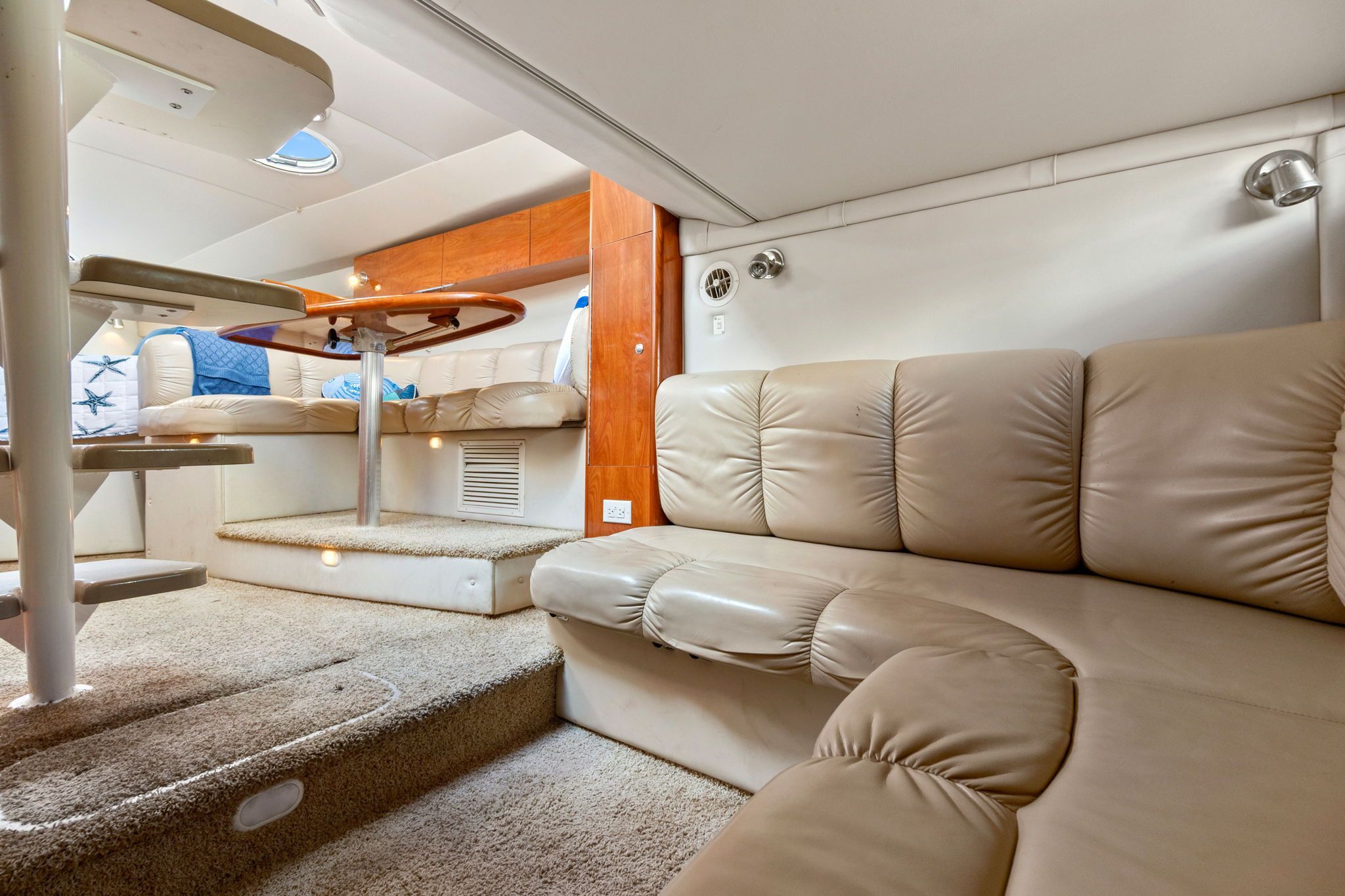 Interior of a 2007 Larson Cabrio 330 with beige leather sofa and carpeted floor.