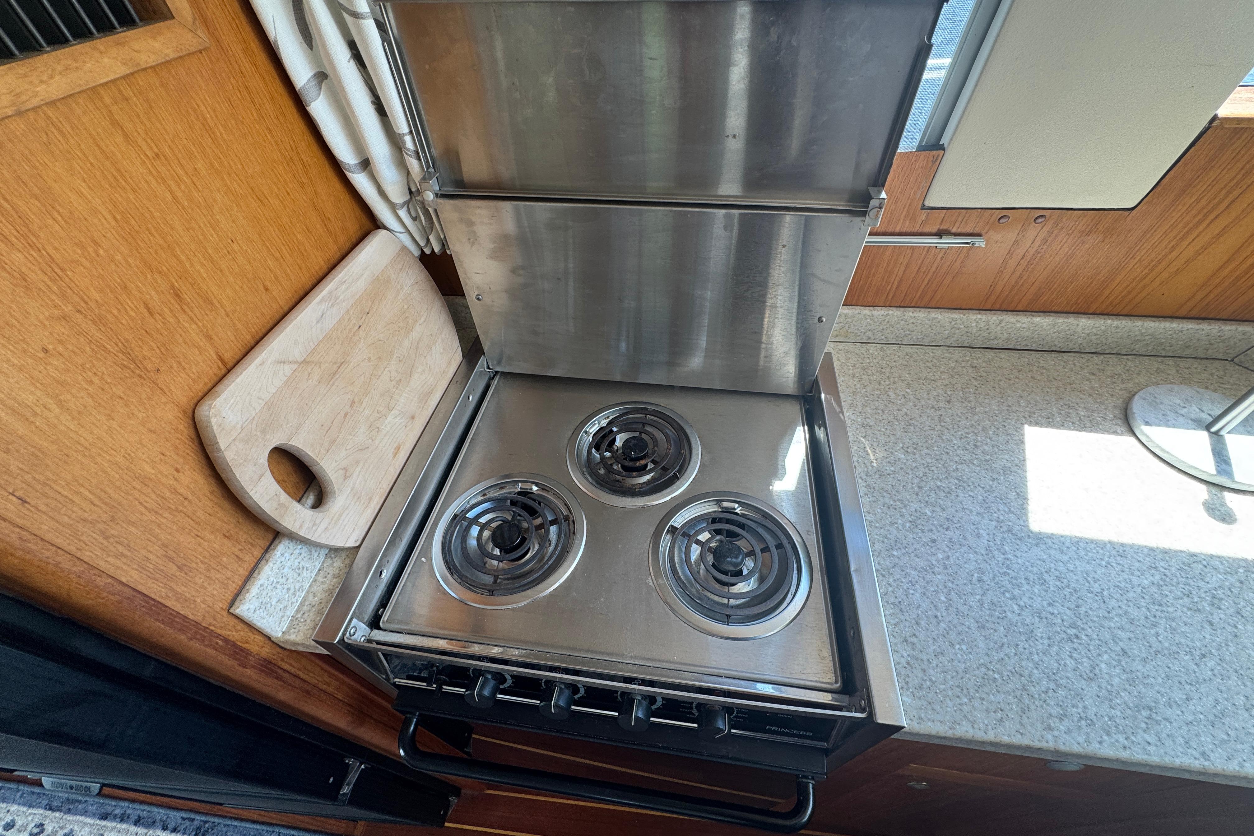 2002 Mainship 390 Trawler kitchen with stainless steel stove and wooden cutting board.