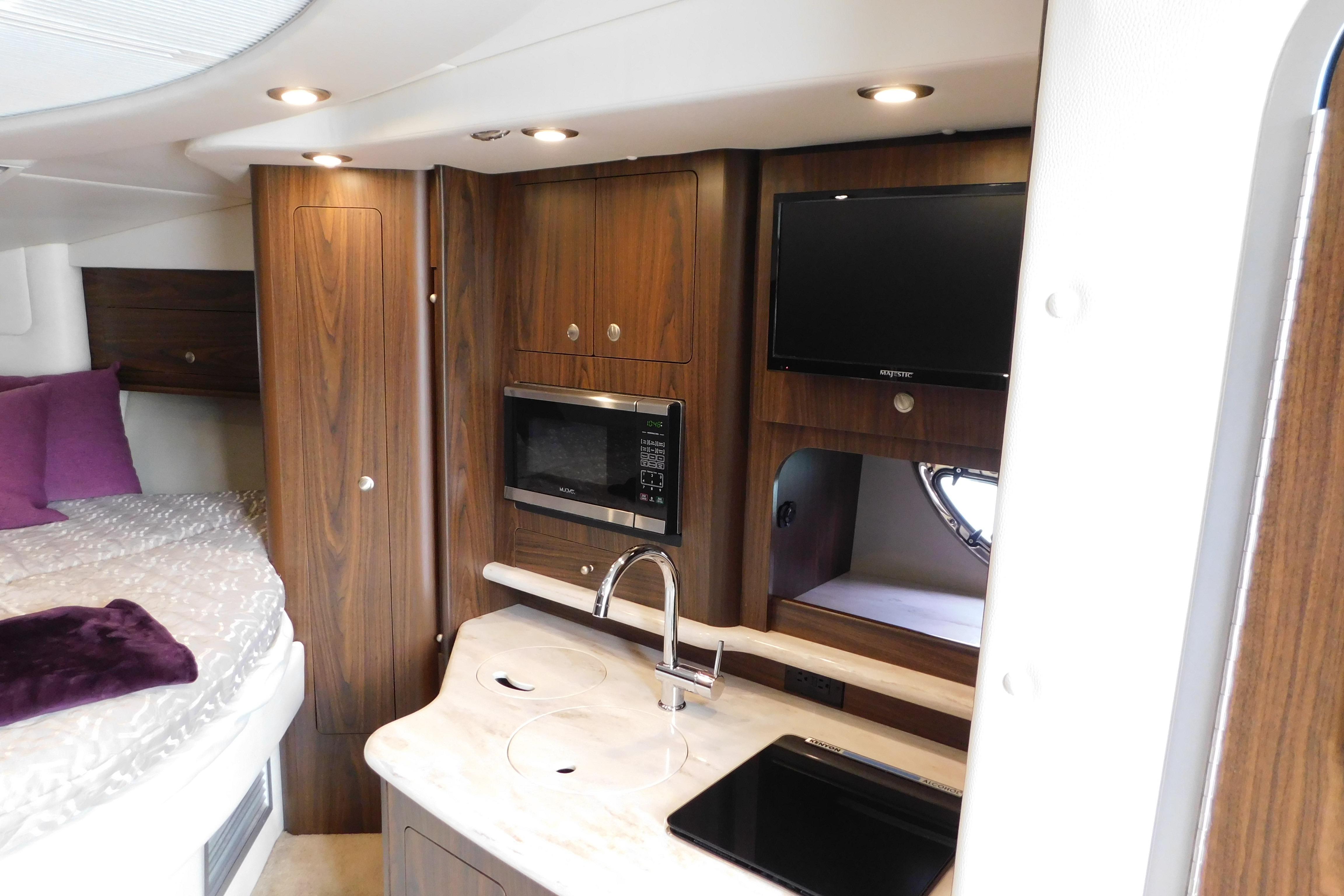 2017 Rinker EX 320 cabin interior with kitchenette, TV, and bed.