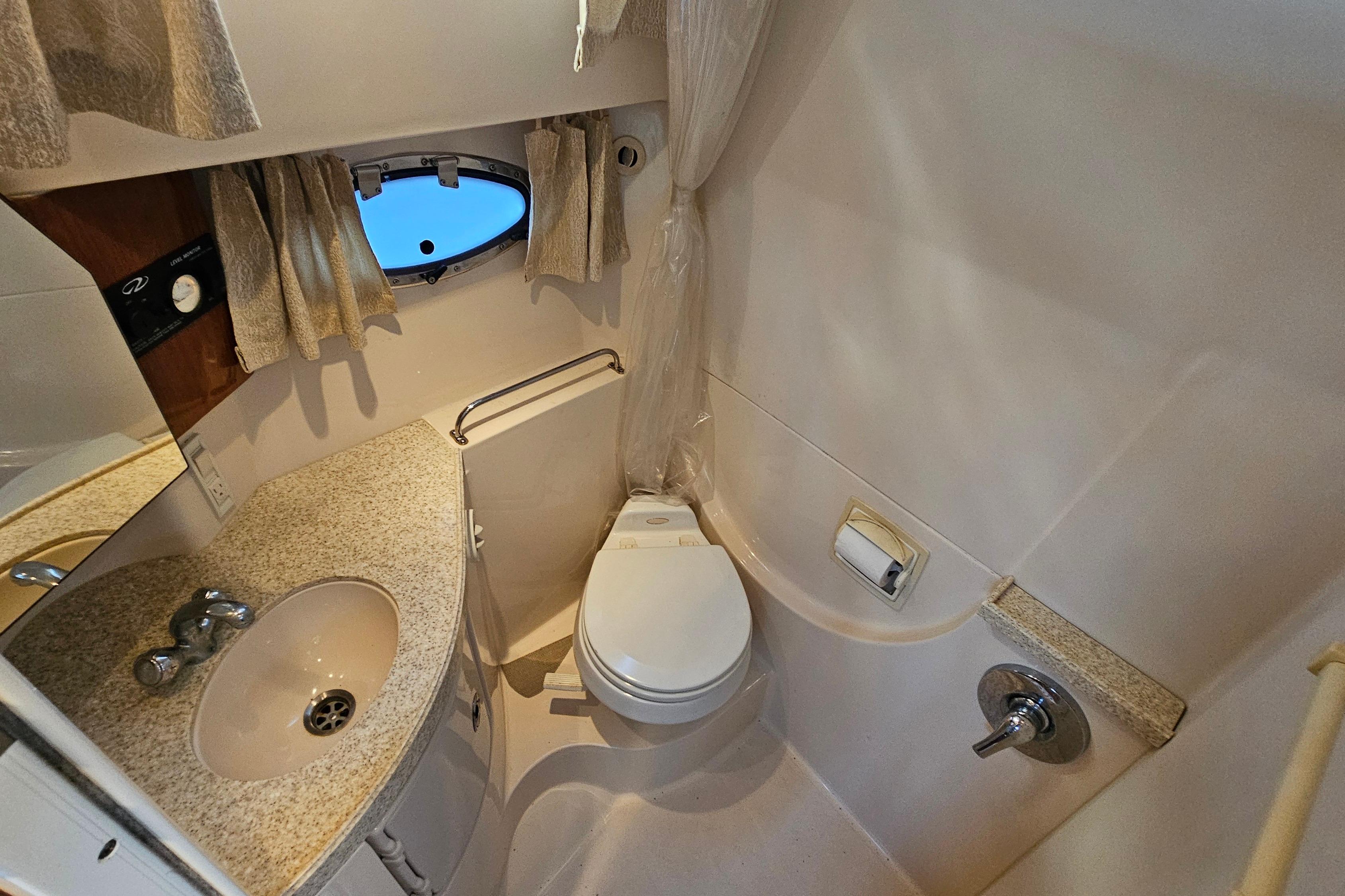 2005 Regal 3060 Window Express boat bathroom with sink, toilet, and porthole window.
