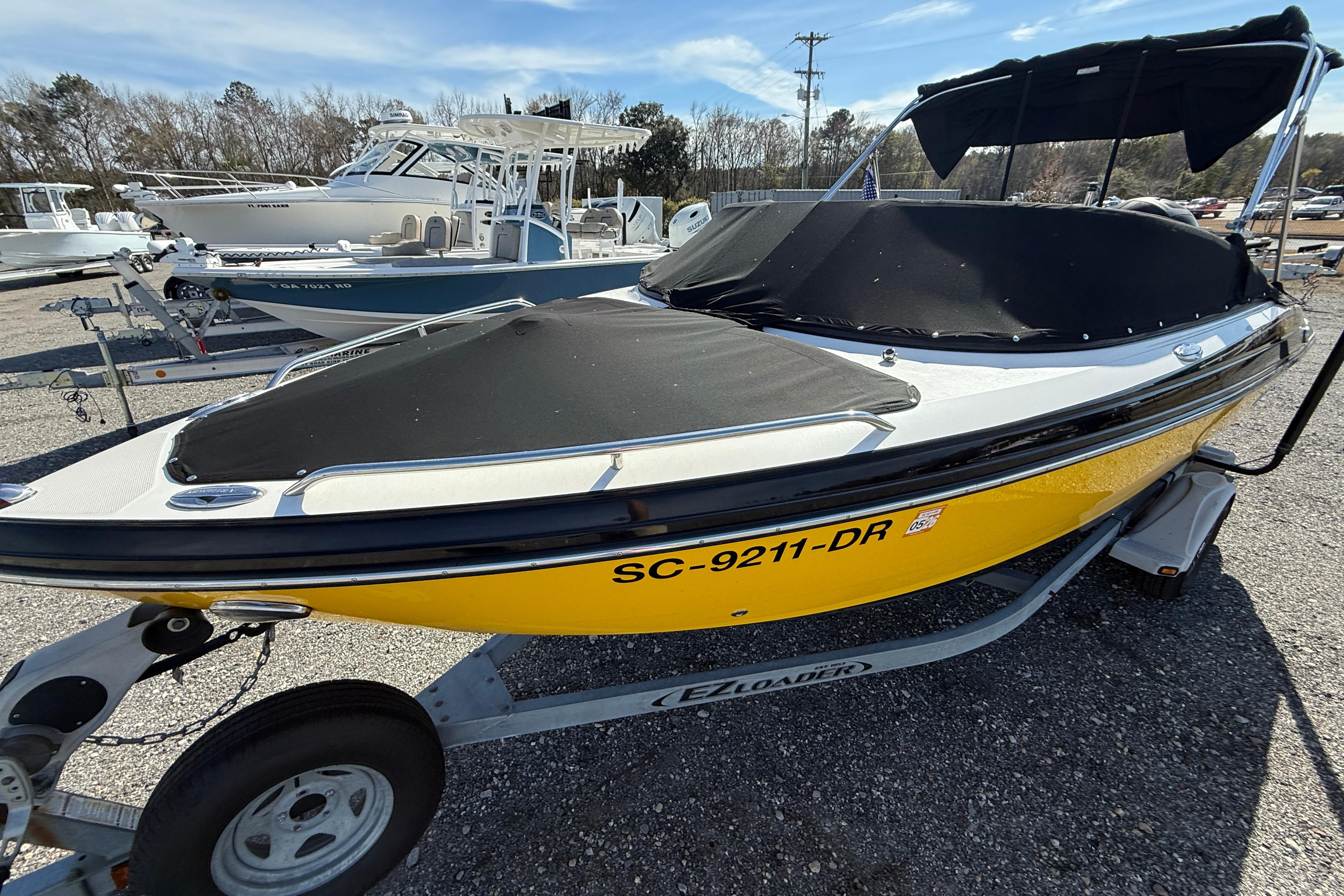 2014 Monterey 197 Blackfin boat with yellow hull on trailer, covered and parked outdoors.