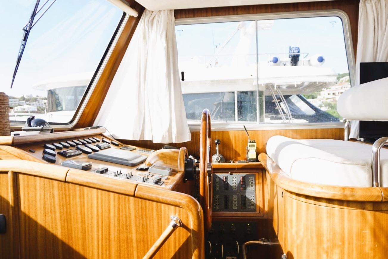 Interior view of 2006 Menorquin Yacht 180 cockpit with wooden dashboard and steering wheel.