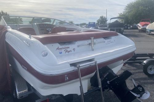 1997 Sea Ray 230 Overnighter boat with maroon accents, parked on a trailer.