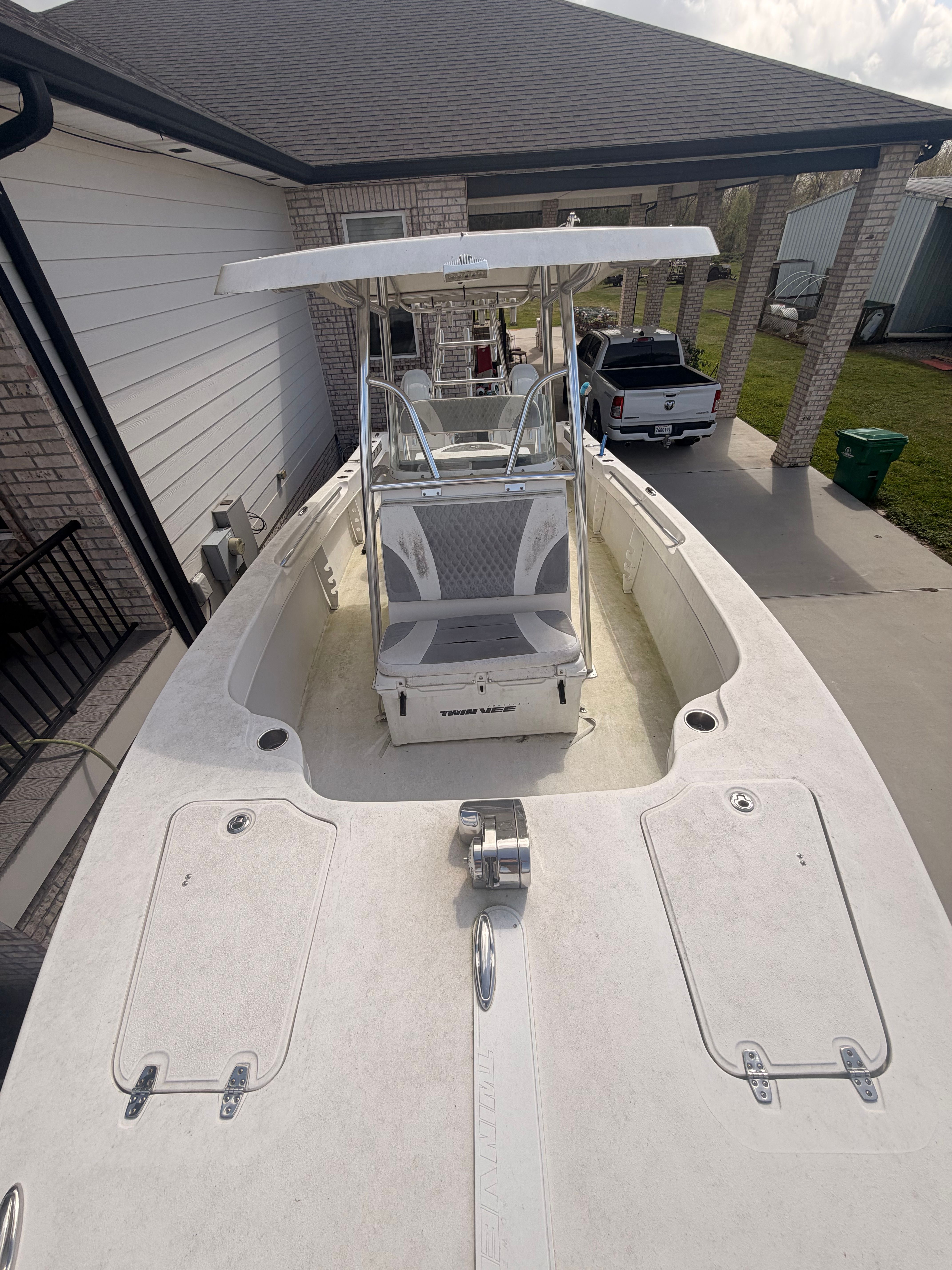 A Twin Vee Ocean Cat boat is on a trailer next to a house.