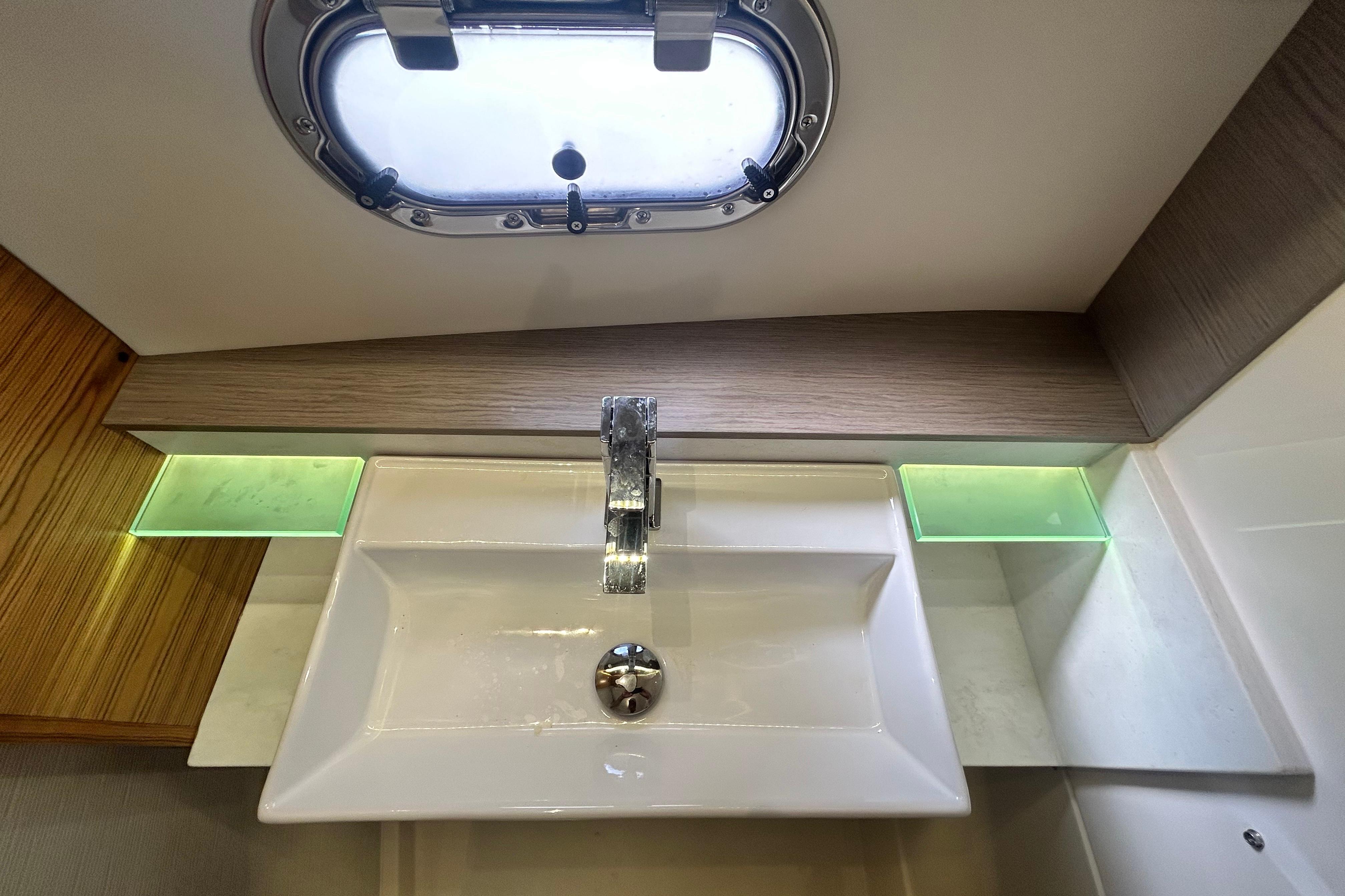 Modern bathroom sink in 2023 Tiara Yachts 38 LS, featuring sleek design and porthole window.
