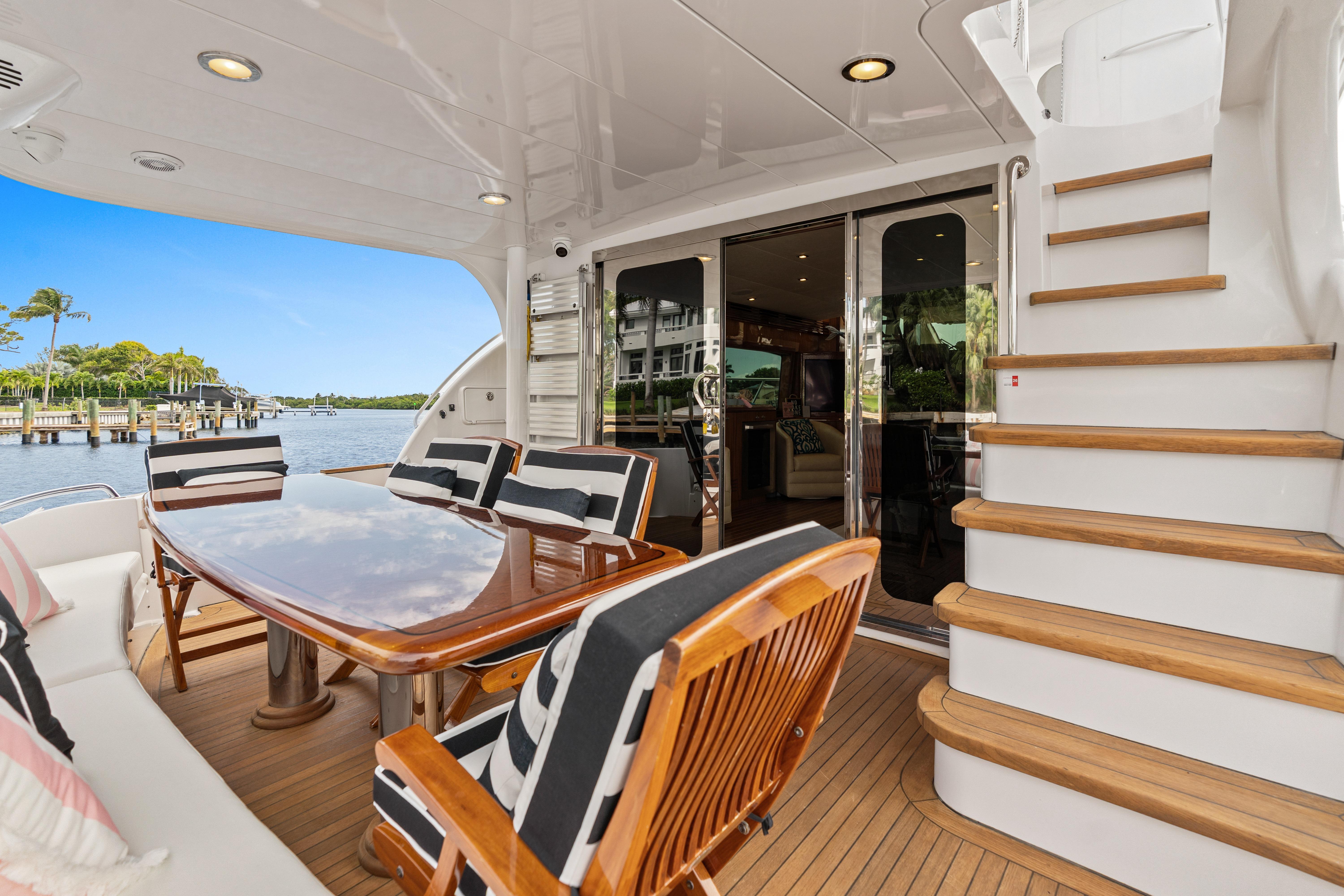 2008 Hatteras 64 Motor Yacht deck with dining area and scenic waterfront view.