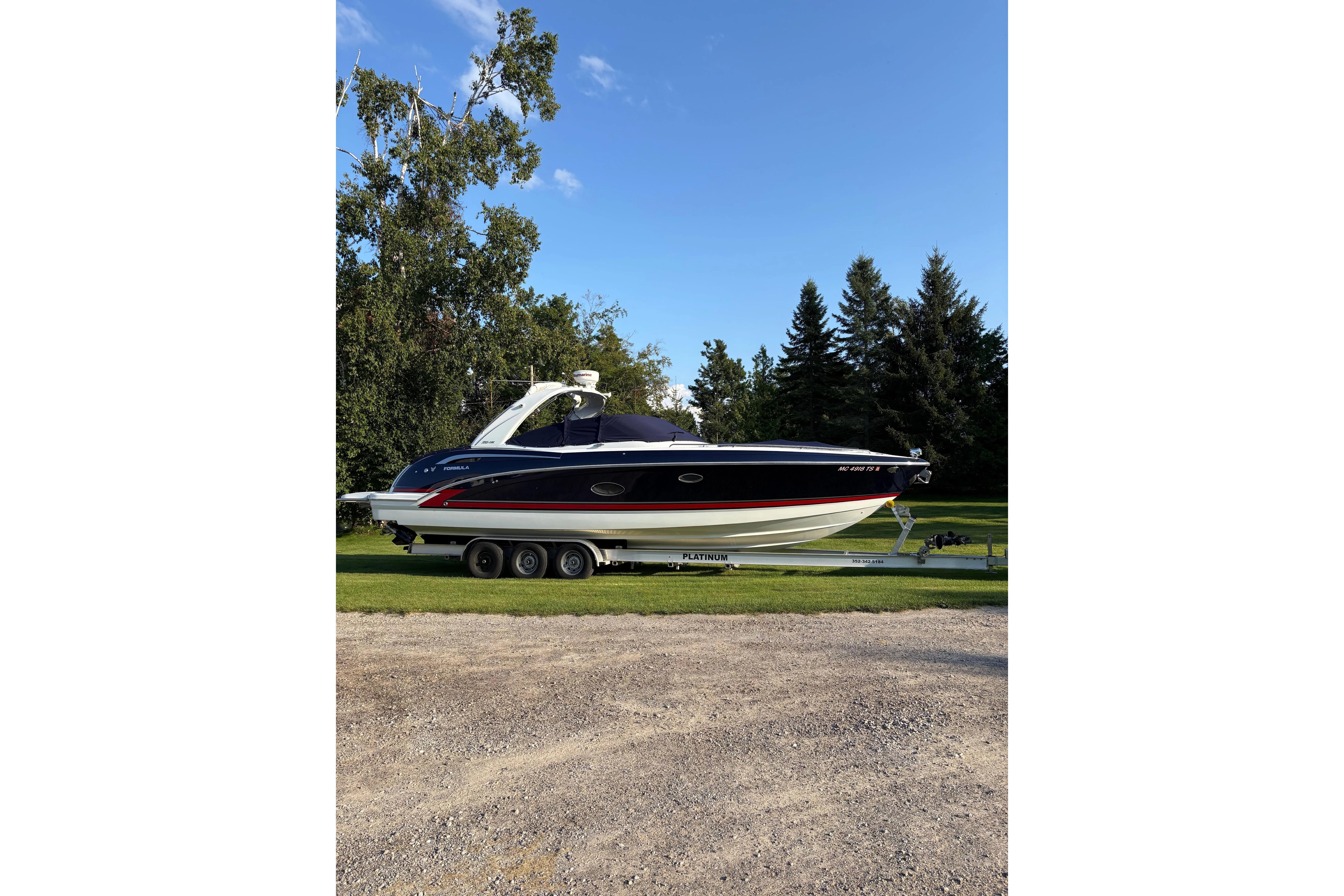 2015 Formula 350 Crossover Bowrider on trailer, parked on grass with trees in background.