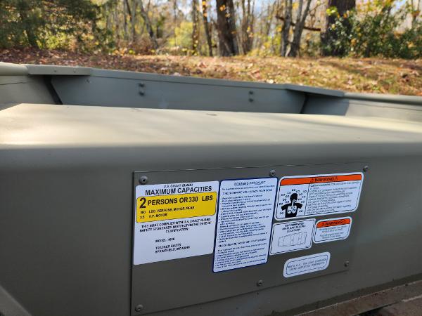 2025 Tracker Grizzly 1036 Utility boat with capacity and safety labels in a wooded area.