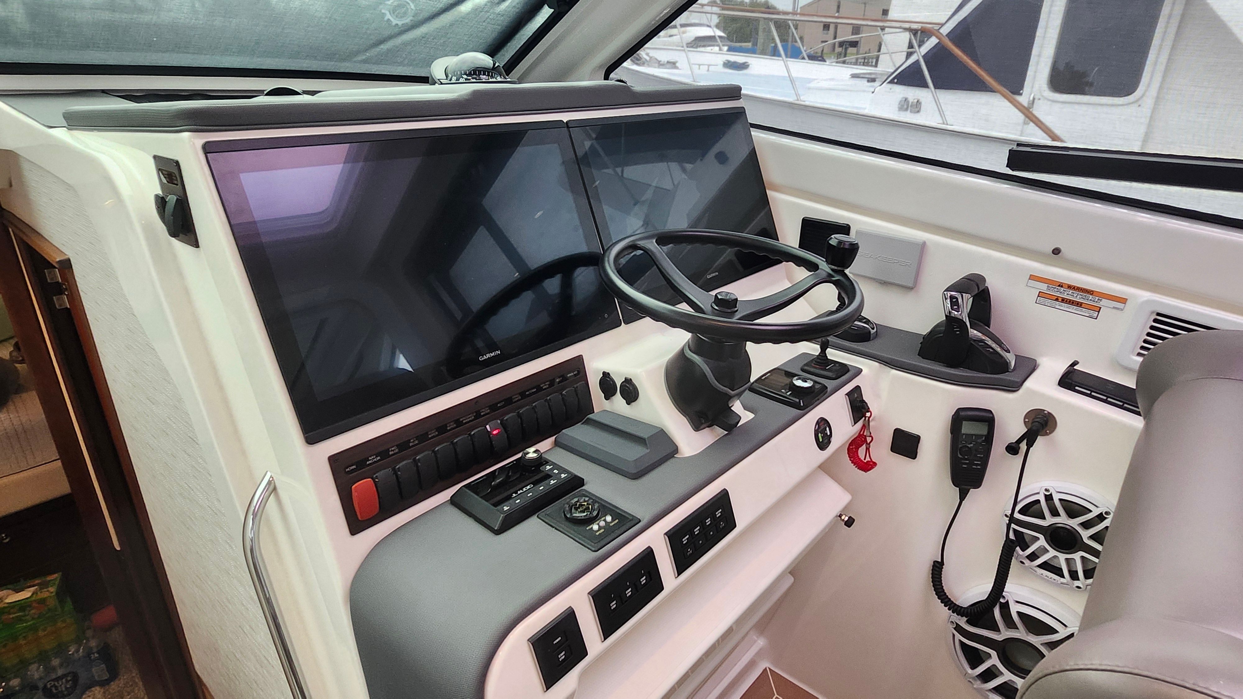 The image shows the helm of a Pursuit OS 445 Offshore with modern instruments and a steering wheel.